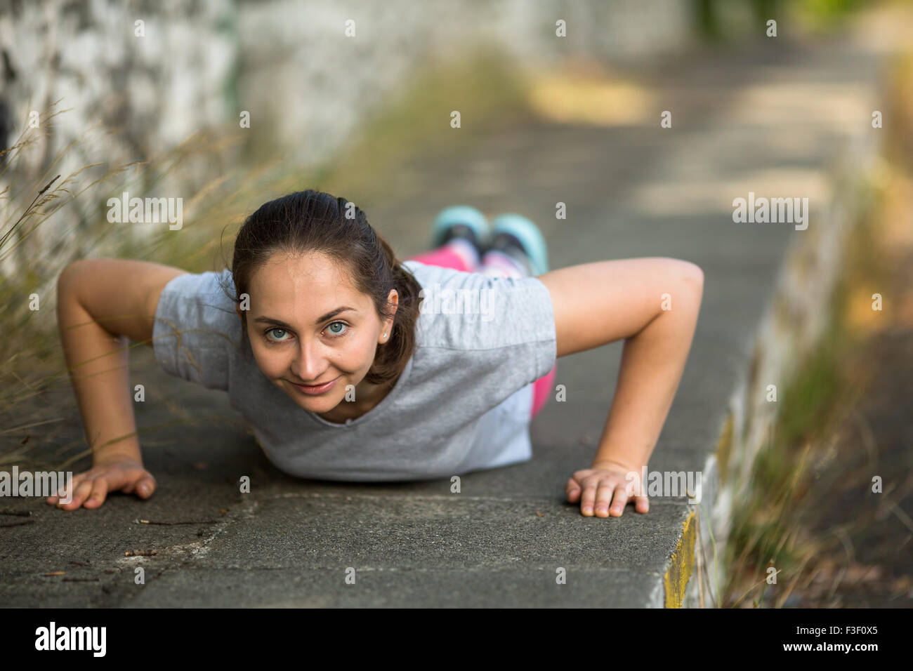 Young Girl doing push-ups au cours de l'échauffement avant le jogging dans le parc. Mode de vie sain. Banque D'Images