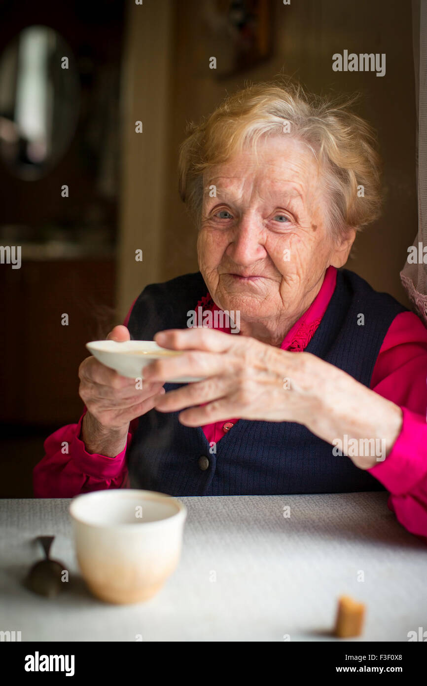 Portrait d'une vieille femme à boire le thé à une table dans la cuisine. Banque D'Images