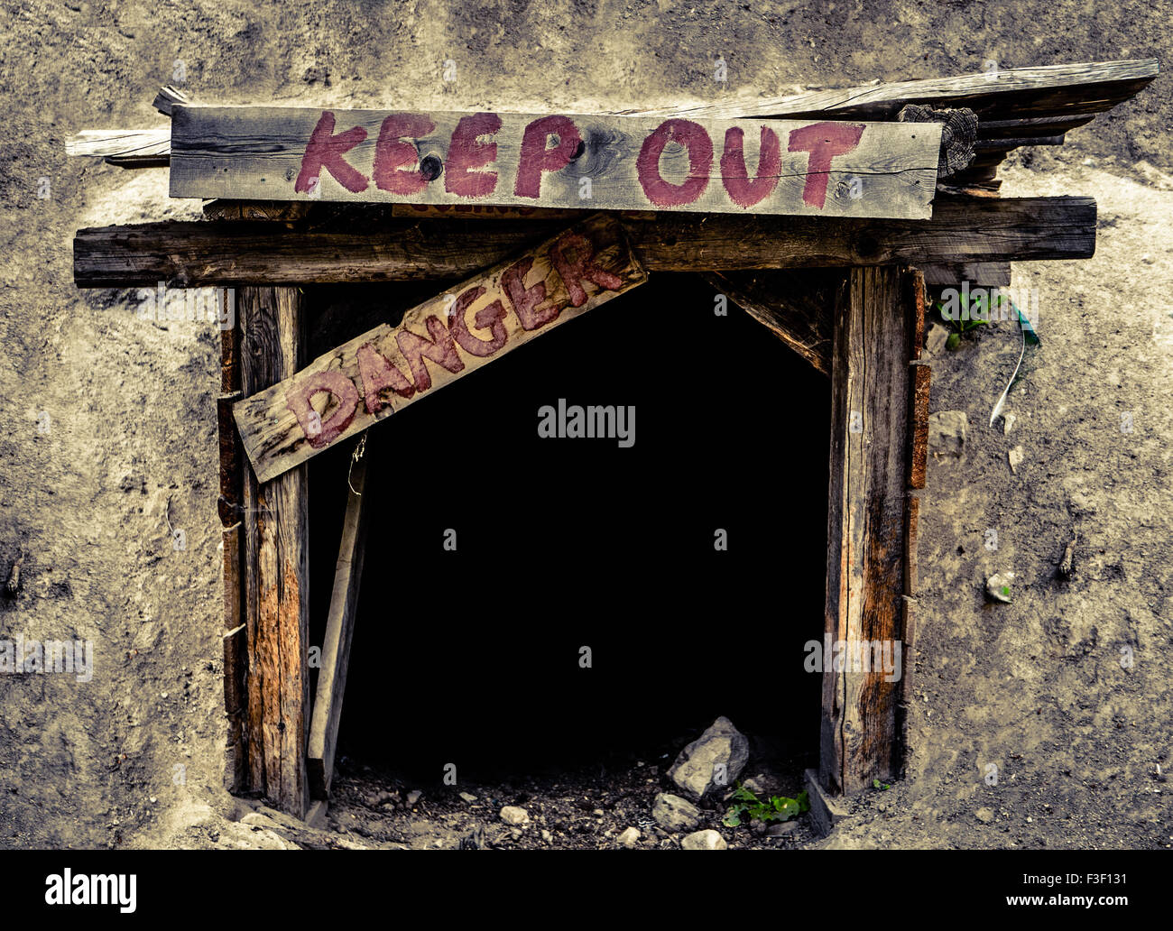 Image conceptuelle d'une l'entrée d'une vieille mine Tunnel Avec Garder hors et signes de danger Banque D'Images