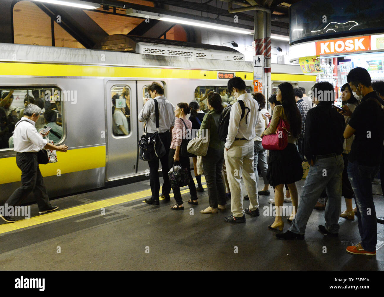 Une plate-forme occupée au cours de la soirée, aux heures de pointe dans la gare de Shinjuku, Tokyo. Banque D'Images