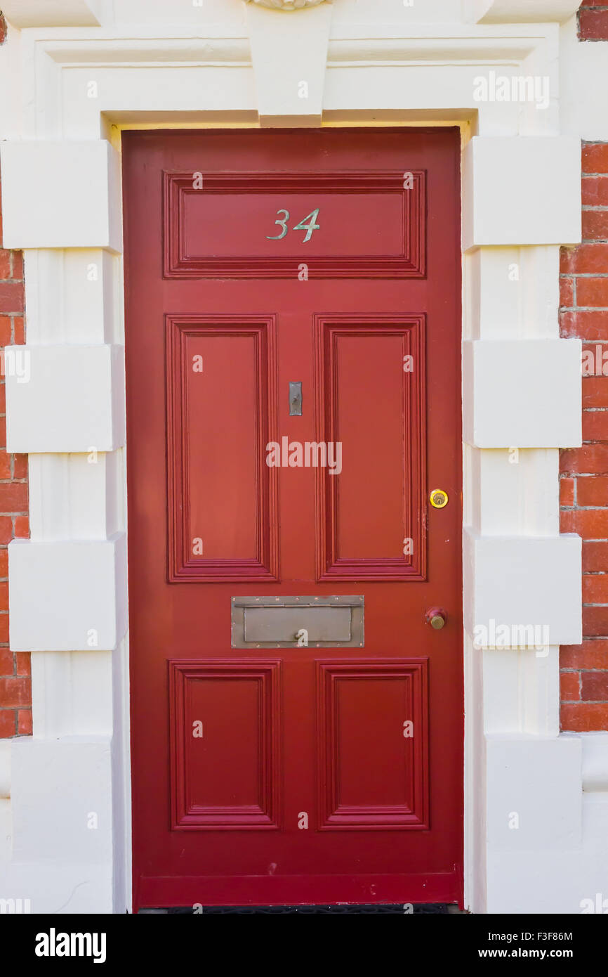 La porte Rouge Blanc avec cadre de porte et bouton gris sur un fond de brique Banque D'Images