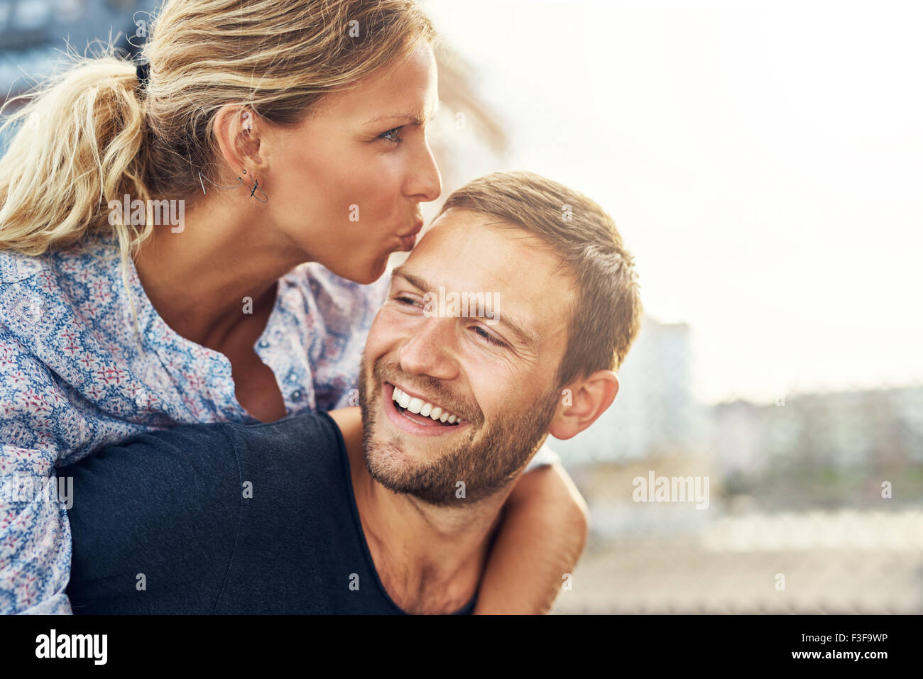 Woman Kissing Man alors qu'il rit, jeune couple Banque D'Images