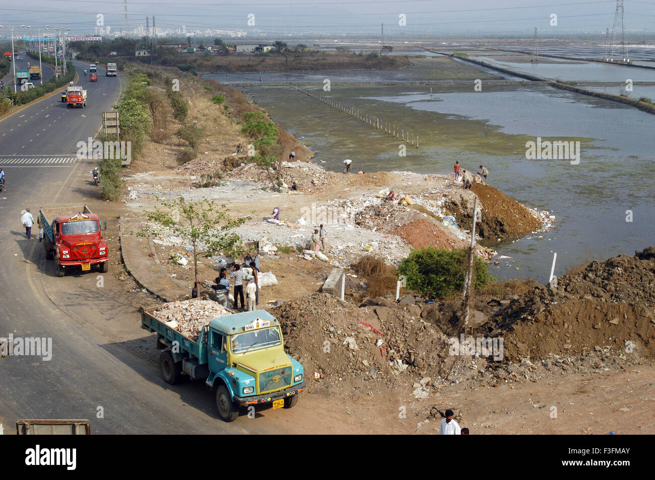 Vidage des camions des débris sur la terre de sel sur le pan est de l'autoroute express à Bombay maintenant Mumbai Maharashtra ; Inde ; Banque D'Images