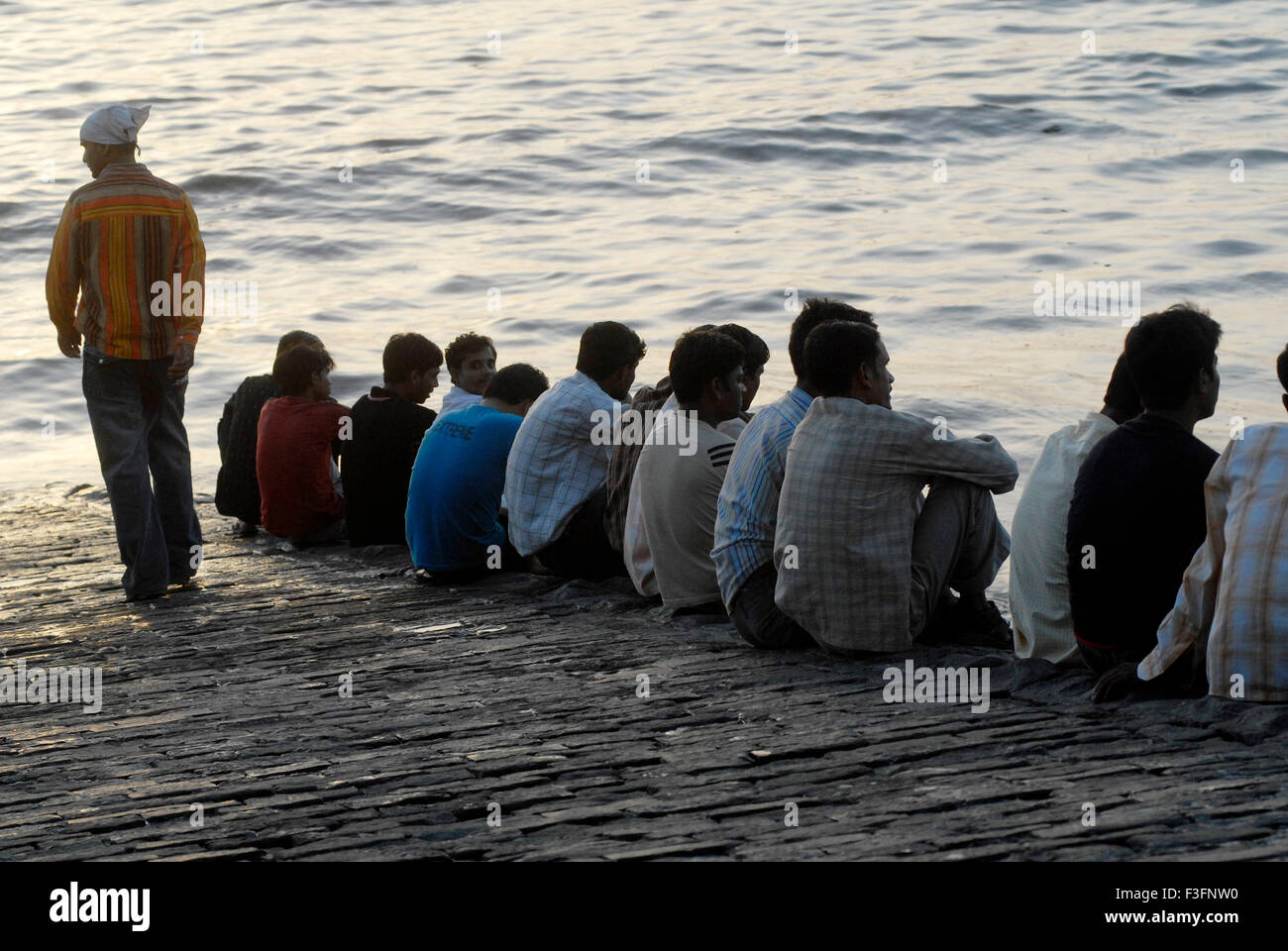 Les gens s'assoient en ligne profitant de la brise marine à Mahim Beach sur la mer d'Oman dans Bombay Mumbai Maharashtra ; Inde ; Banque D'Images