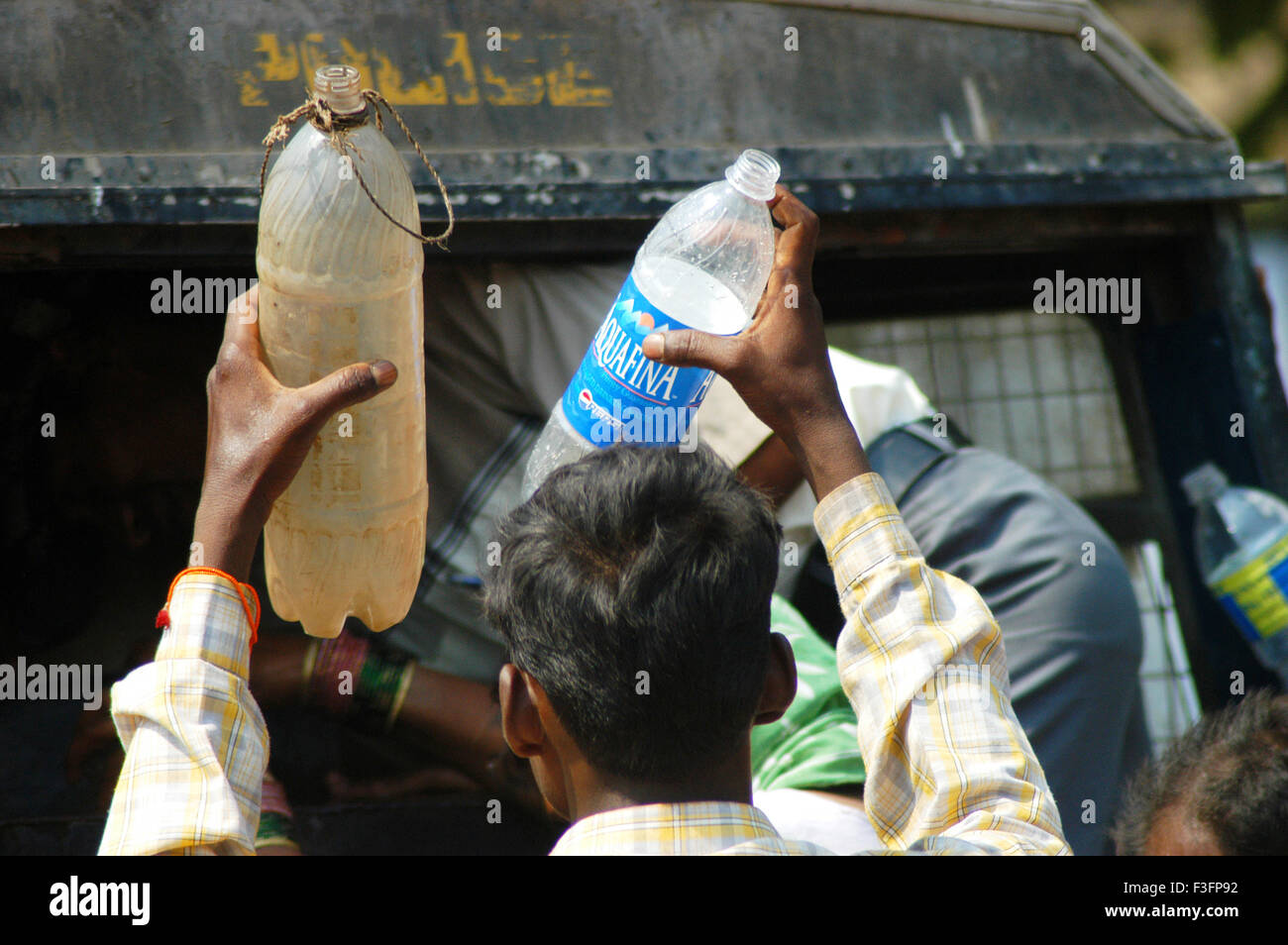 Pauvre homme détient deux bouteilles en plastique à remplir d'eau potable ; Bombay Mumbai Maharashtra ; Inde ; Banque D'Images