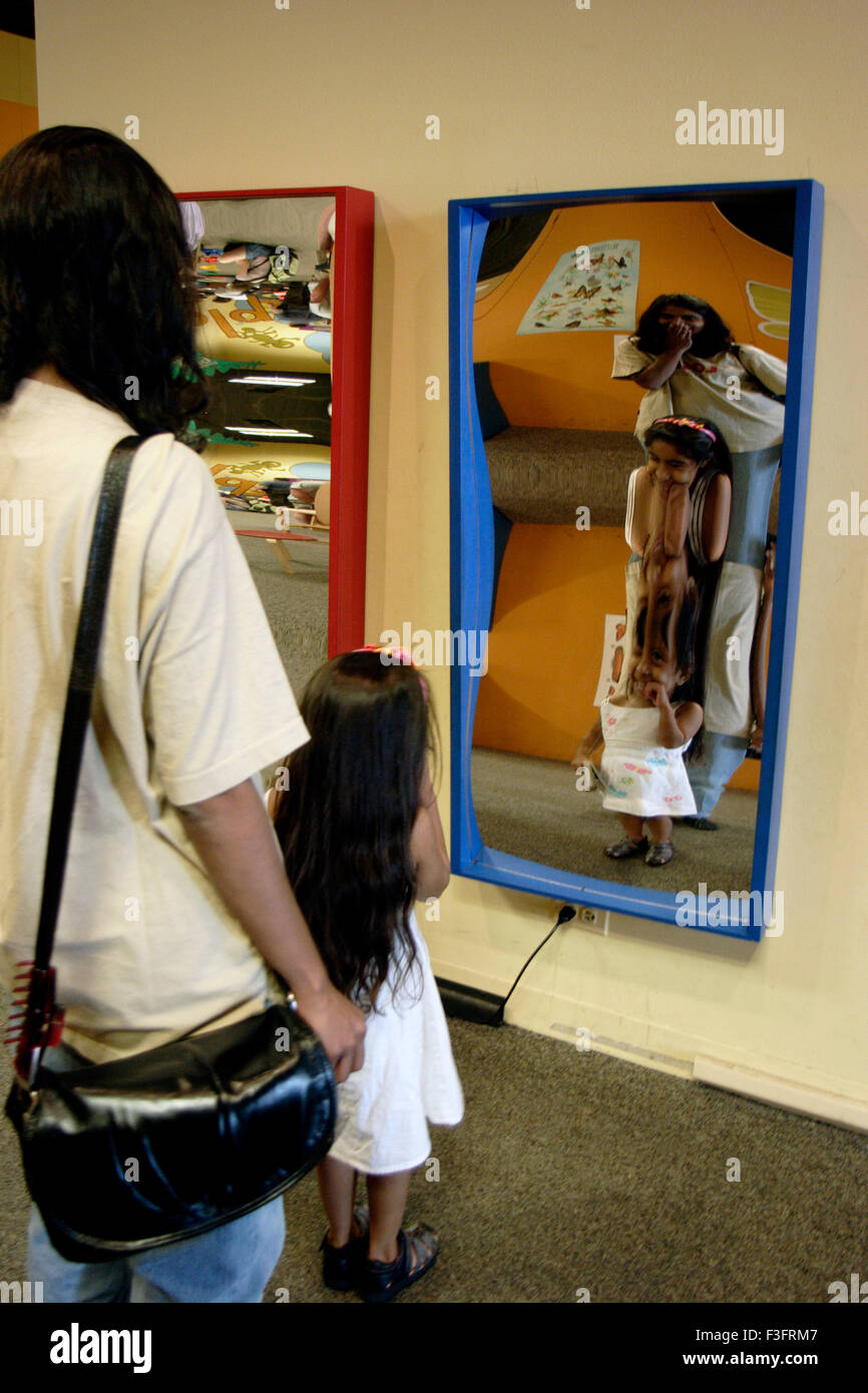 Fille avec mère regardant concave et convexe miroir dans museum Banque D'Images