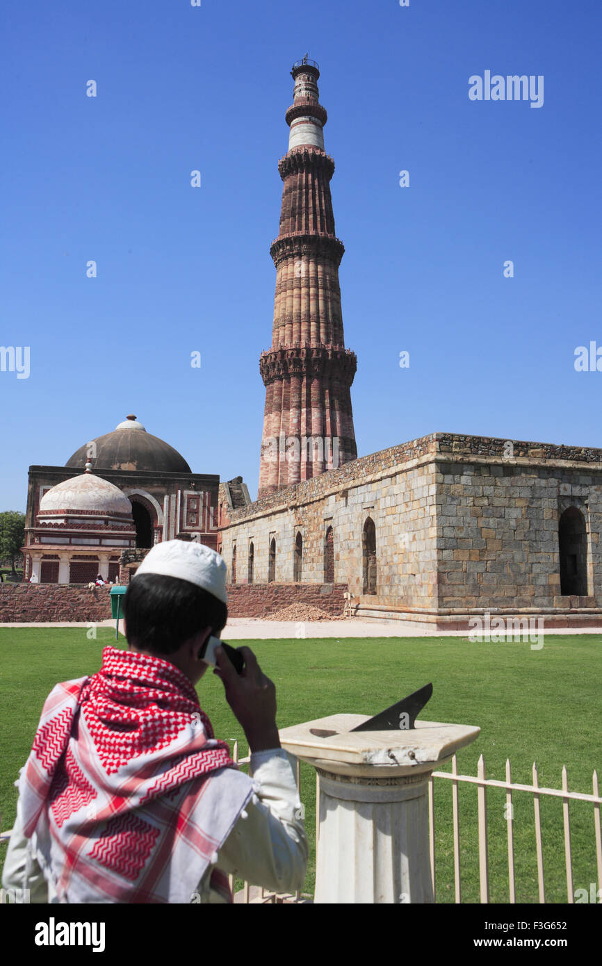 Garçon musulman talking on mobile phone at Qutab Minar cadran solaire construit en 1311 en grès rouge l'art musulman Indo tour Delhi Banque D'Images
