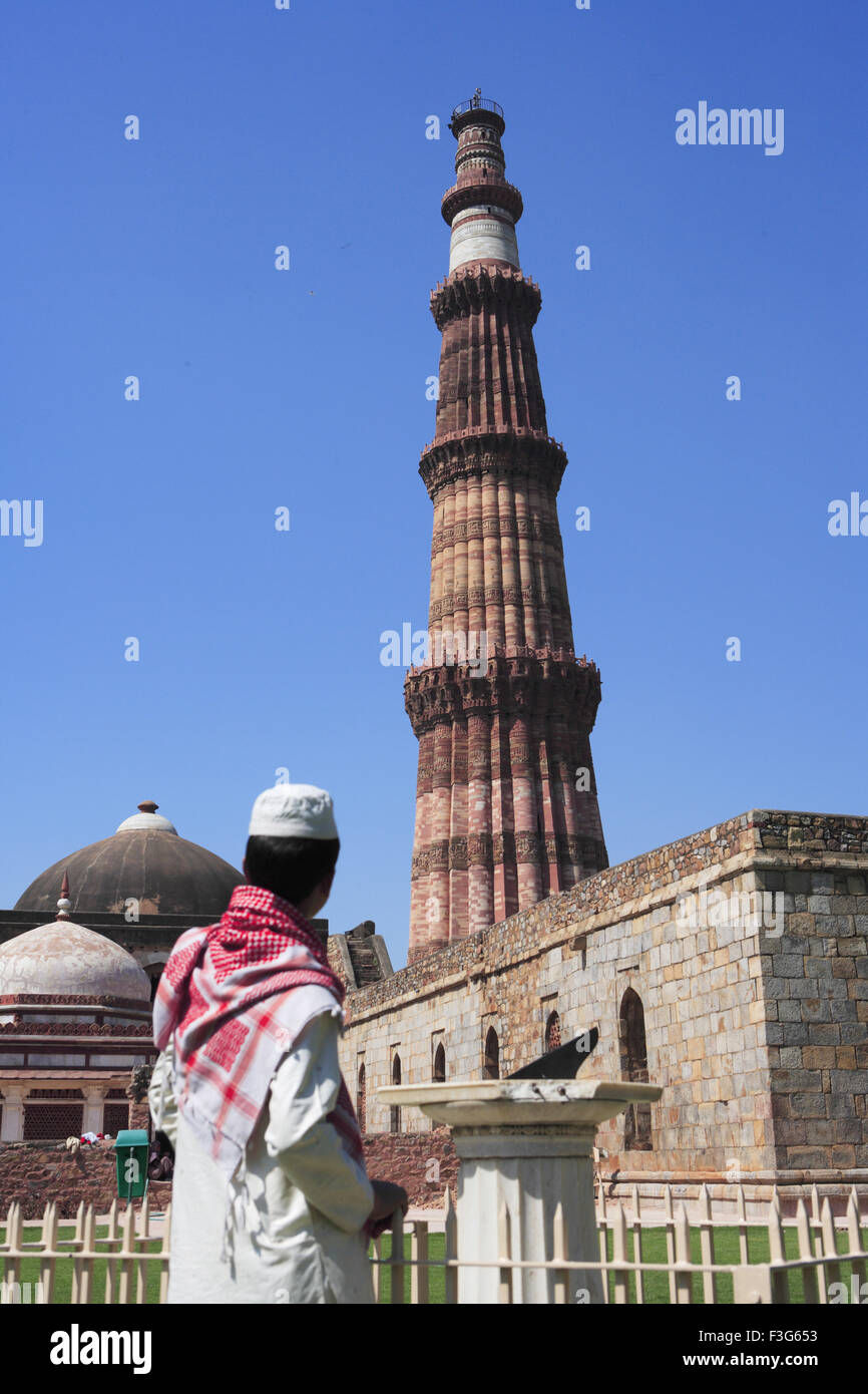 Garçon musulman talking on mobile phone at Qutab Minar cadran solaire construit en 1311 en grès rouge Indo tour Delhi musulman Banque D'Images