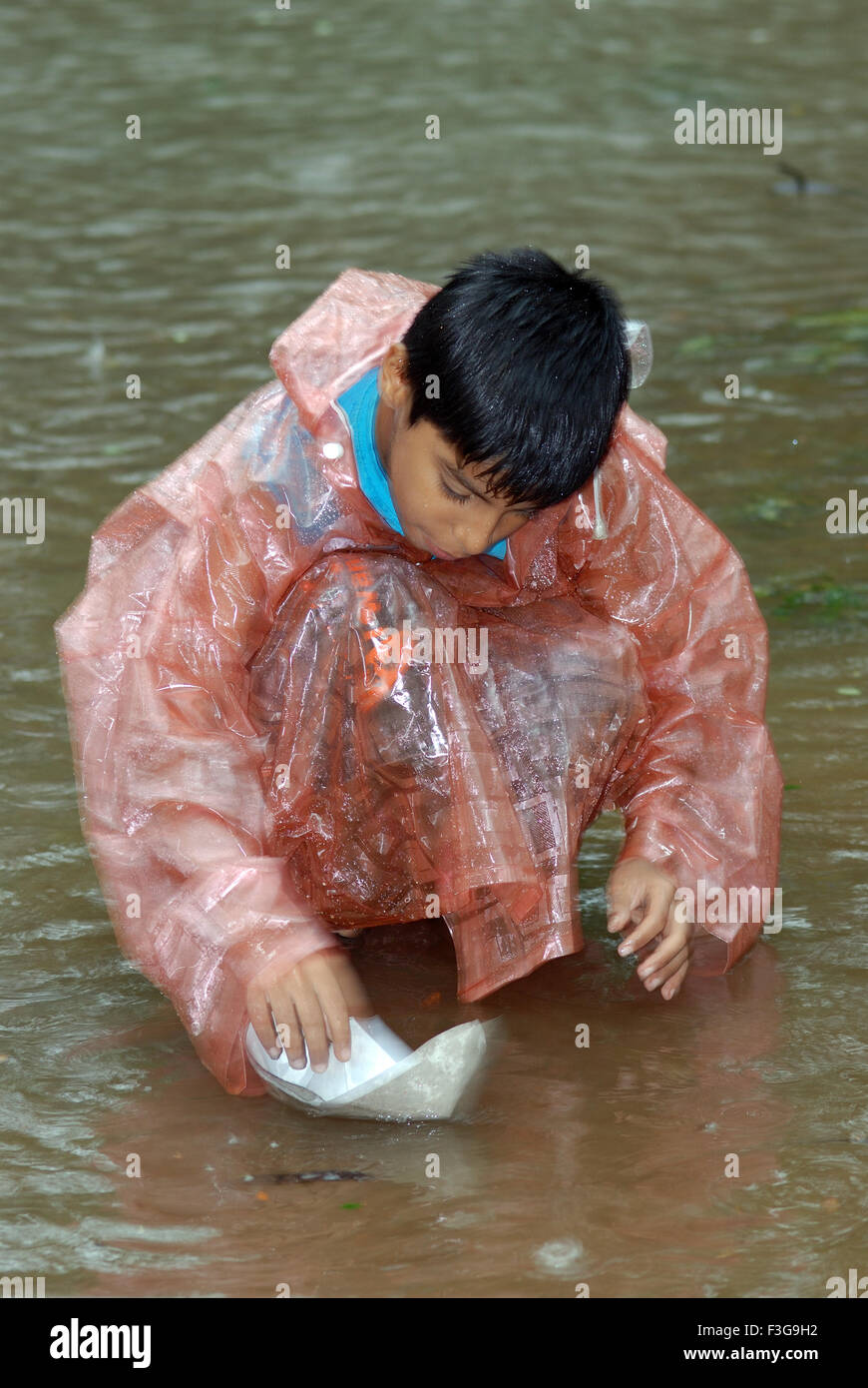 Enfant jouant avec un bateau à papier sous la pluie, Inde, Asie Banque D'Images