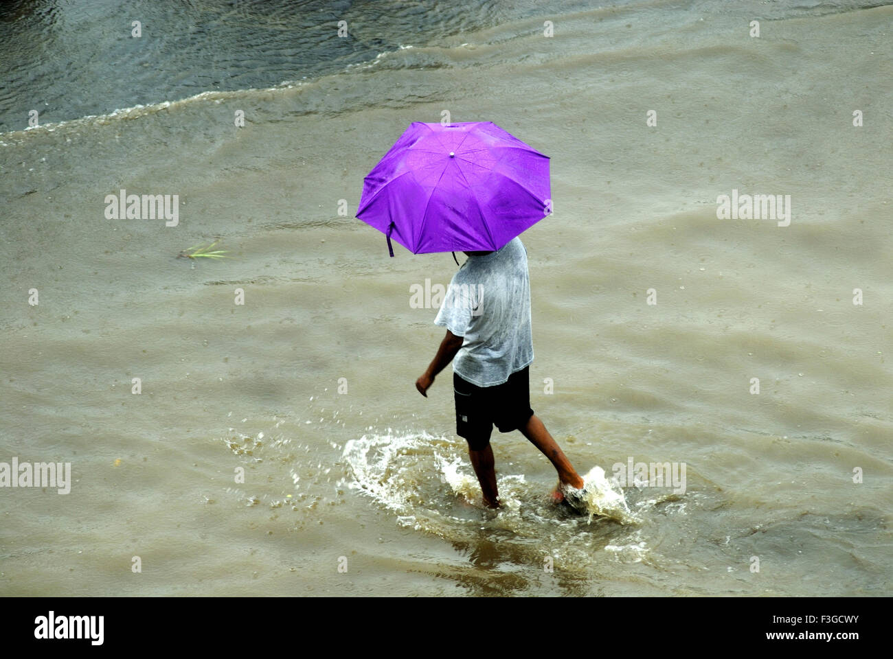 Garçon avec parapluie bleu debout pendant les moussons, inondations à Bandra ; Bombay Mumbai Maharashtra ; Inde ; Banque D'Images