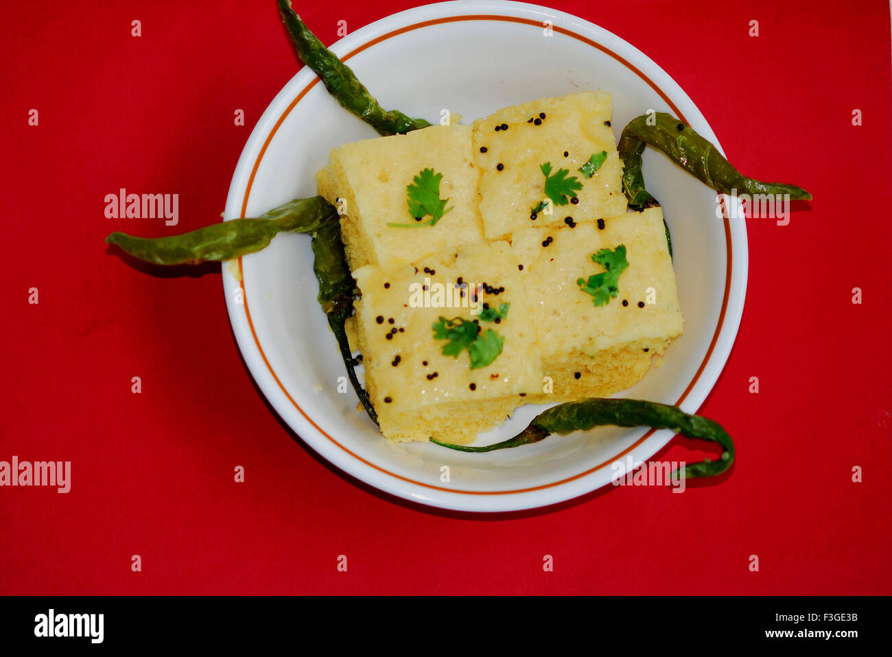 Quatre morceaux de Khaman jaune ou Dhoklas avec piments verts frits servi dans le plat Banque D'Images