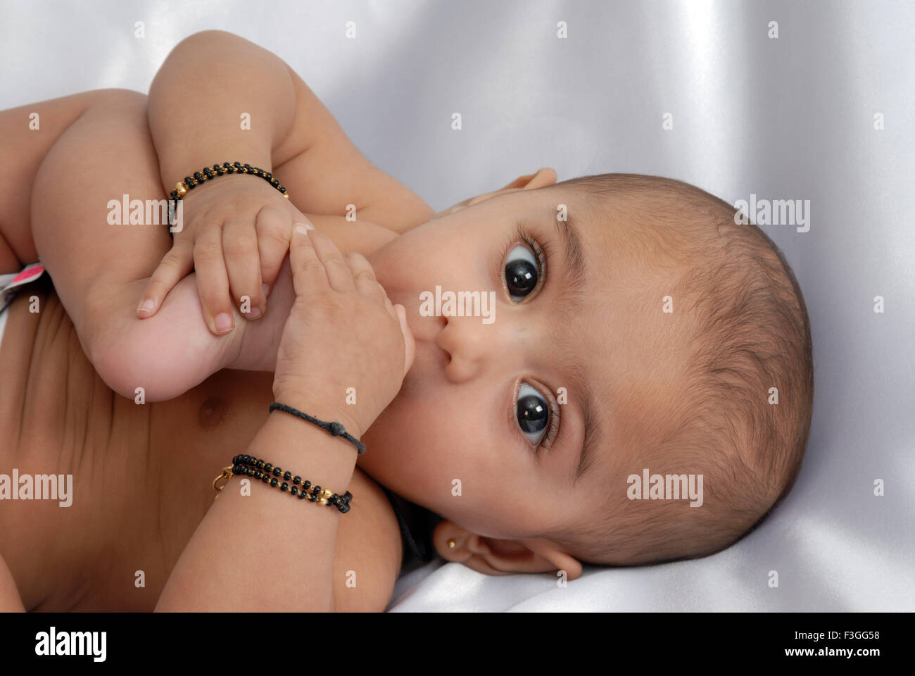 Les Indiens de l'Asie du Sud ; le bébé à mâcher orteil dans sa bouche ; looking at camera ; fond blanc ; Inde M.# 152 Banque D'Images