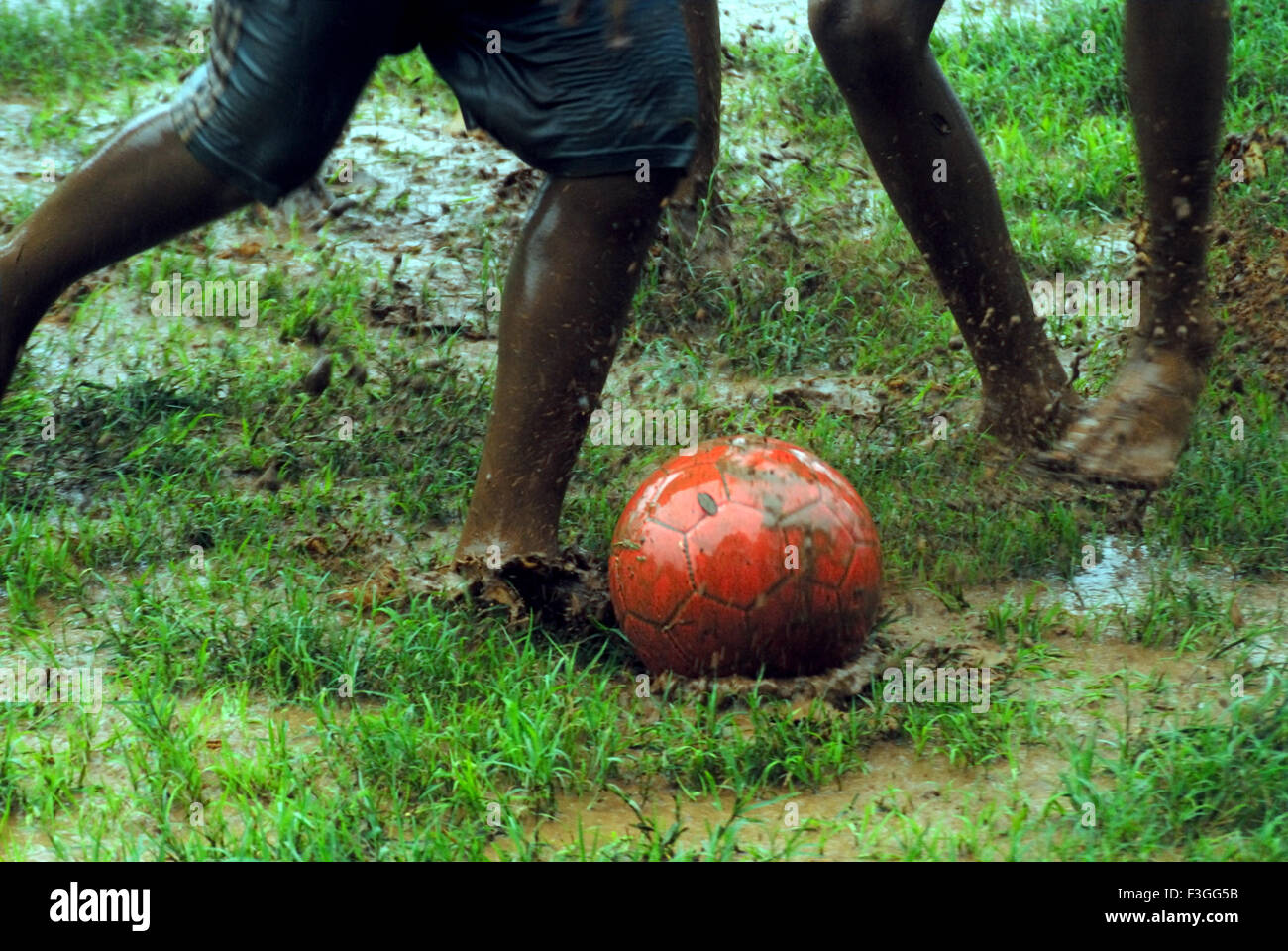 Les Indiens de l'Asie du Sud ; les garçons jouant ; appréciant avec foot ball pendant la mousson ; Inde PAS DE MR Banque D'Images