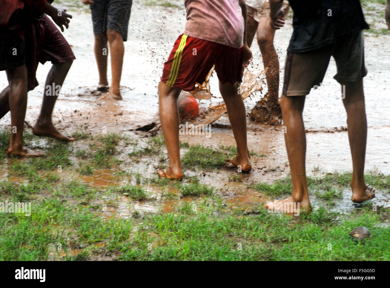 Les Indiens de l'Asie du Sud ; les garçons jouant ; appréciant avec foot ball pendant la mousson ; Inde PAS DE MR Banque D'Images