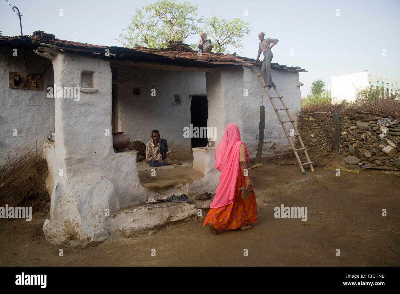 Maison ancienne dans village femme en robe rose marche ; Village ; Dilwara Udaipur Rajasthan ; Inde ; Banque D'Images