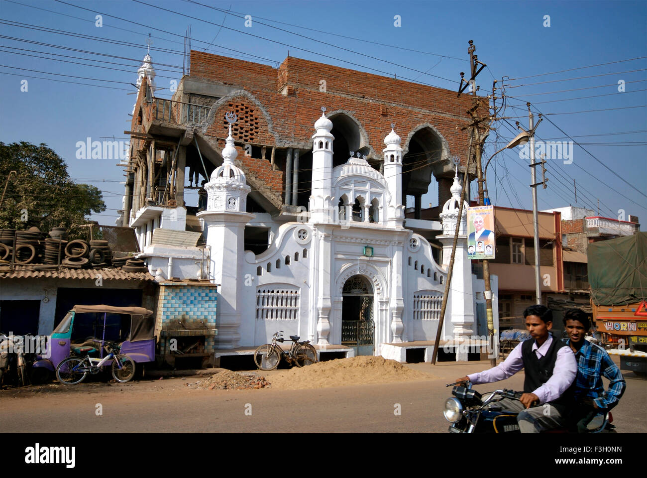 Les motocyclistes ride passé at construction site d'une mosquée ; Katni ; Madhya Pradesh en Inde ; Banque D'Images
