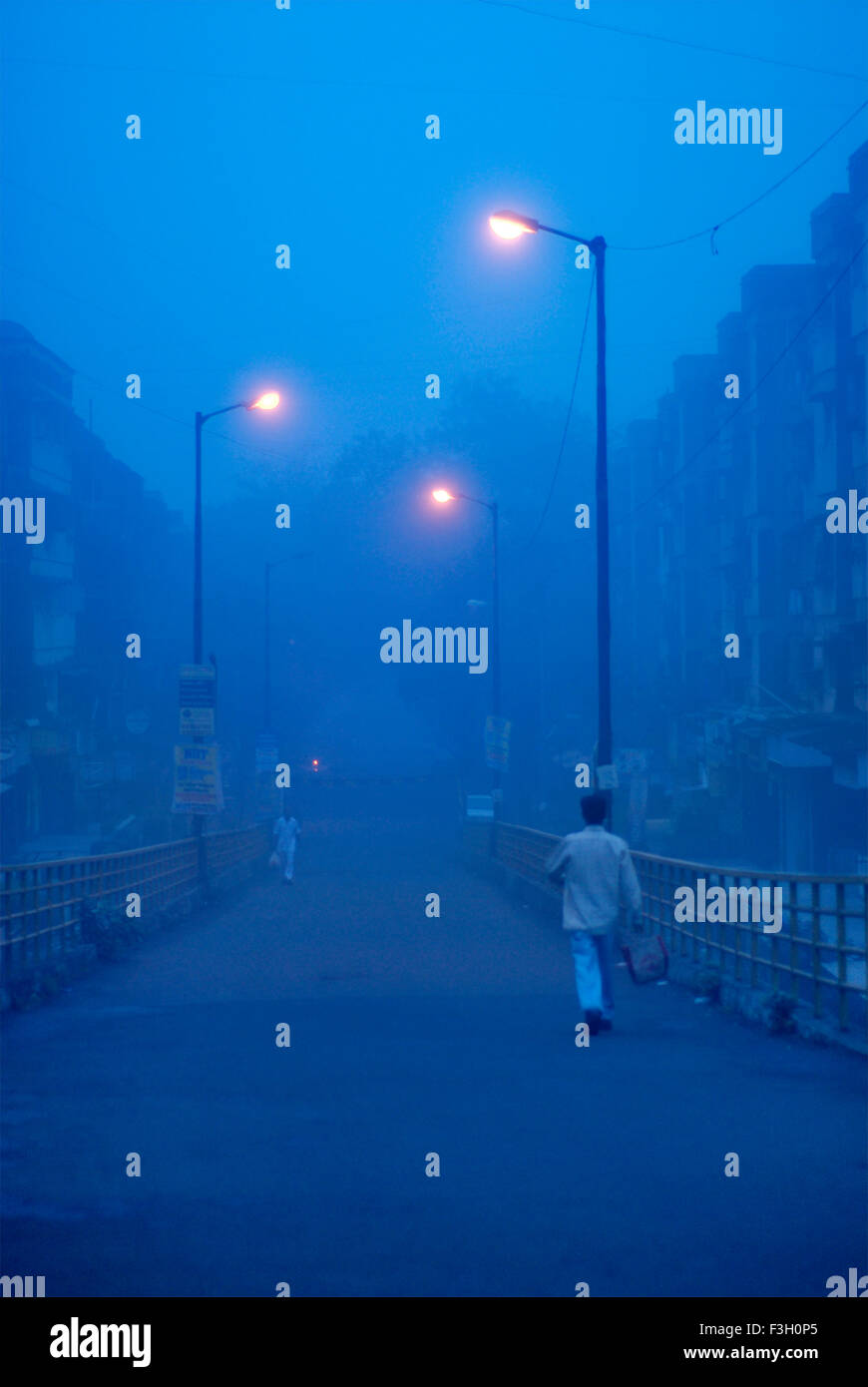 Homme marchant passé sous l'éclairage de rue lumineux matin brumeux ; bleu ; Mulund Bombay Mumbai Maharashtra ; Inde ; Banque D'Images