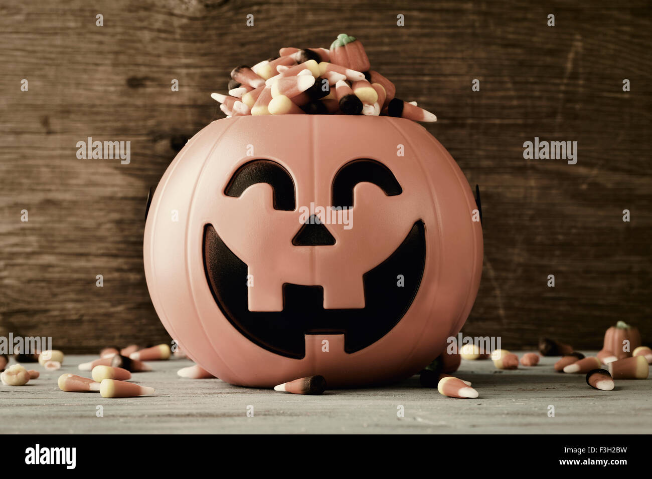 Une citrouille sculptée plein de bonbons halloween différents, sur un fond de bois rustique, avec un effet de filtre Banque D'Images