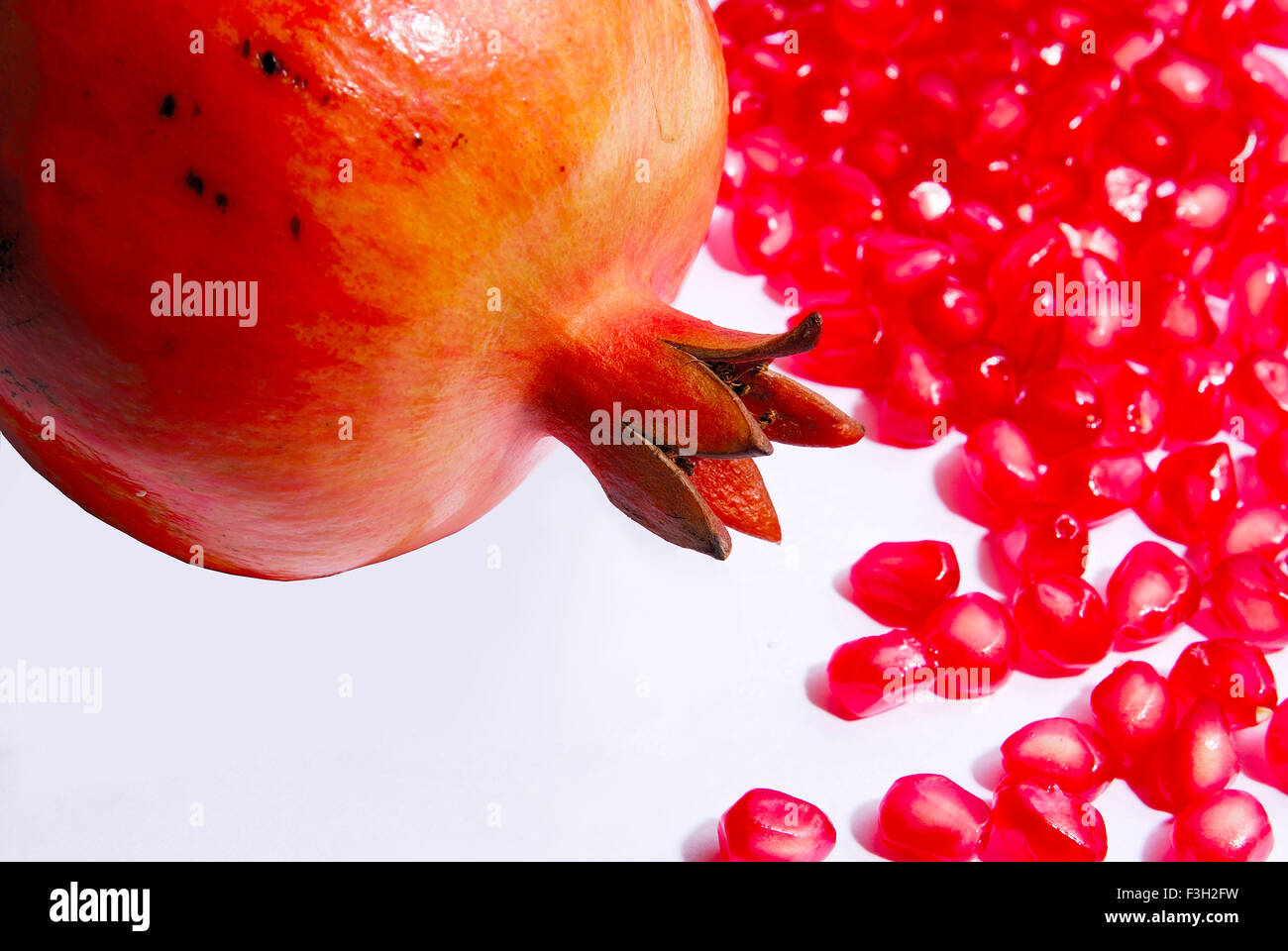 Une grenade complète ; fruits et graines sur fond blanc Banque D'Images