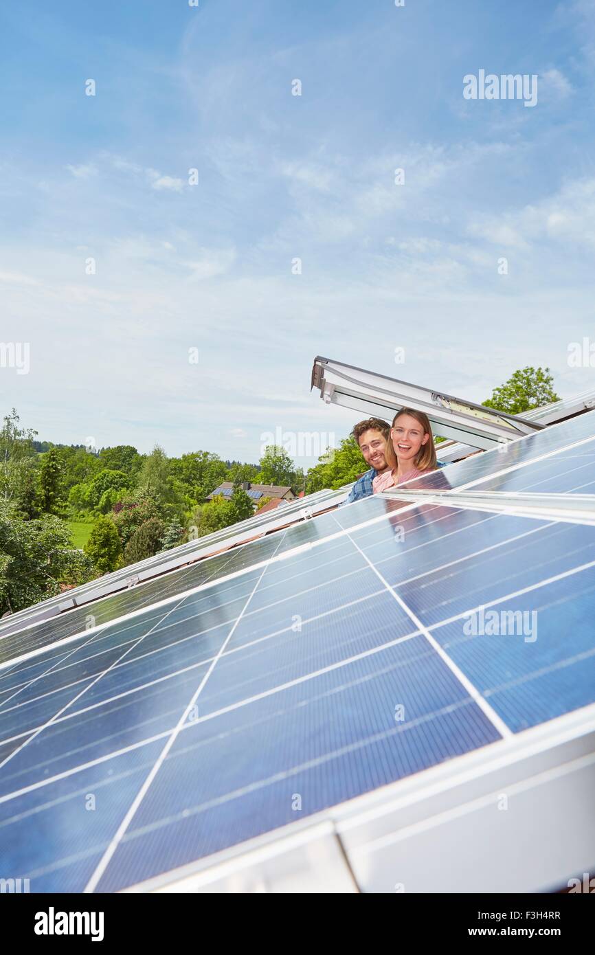 Jeune couple à la recherche de la fenêtre de toit avec des panneaux solaires Banque D'Images