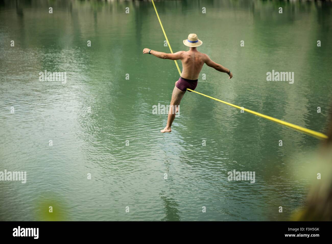 Homme mûr en équilibre sur corde sur le lac, vue arrière Banque D'Images