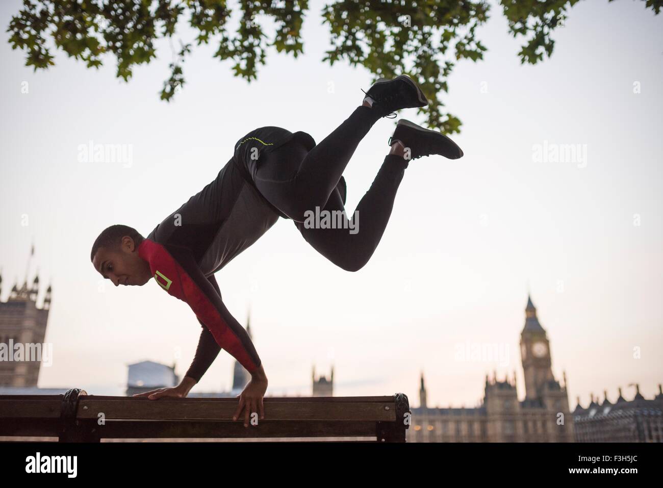 Jeune homme saute au-dessus de banc de parc sur Southbank, Londres, UK Banque D'Images