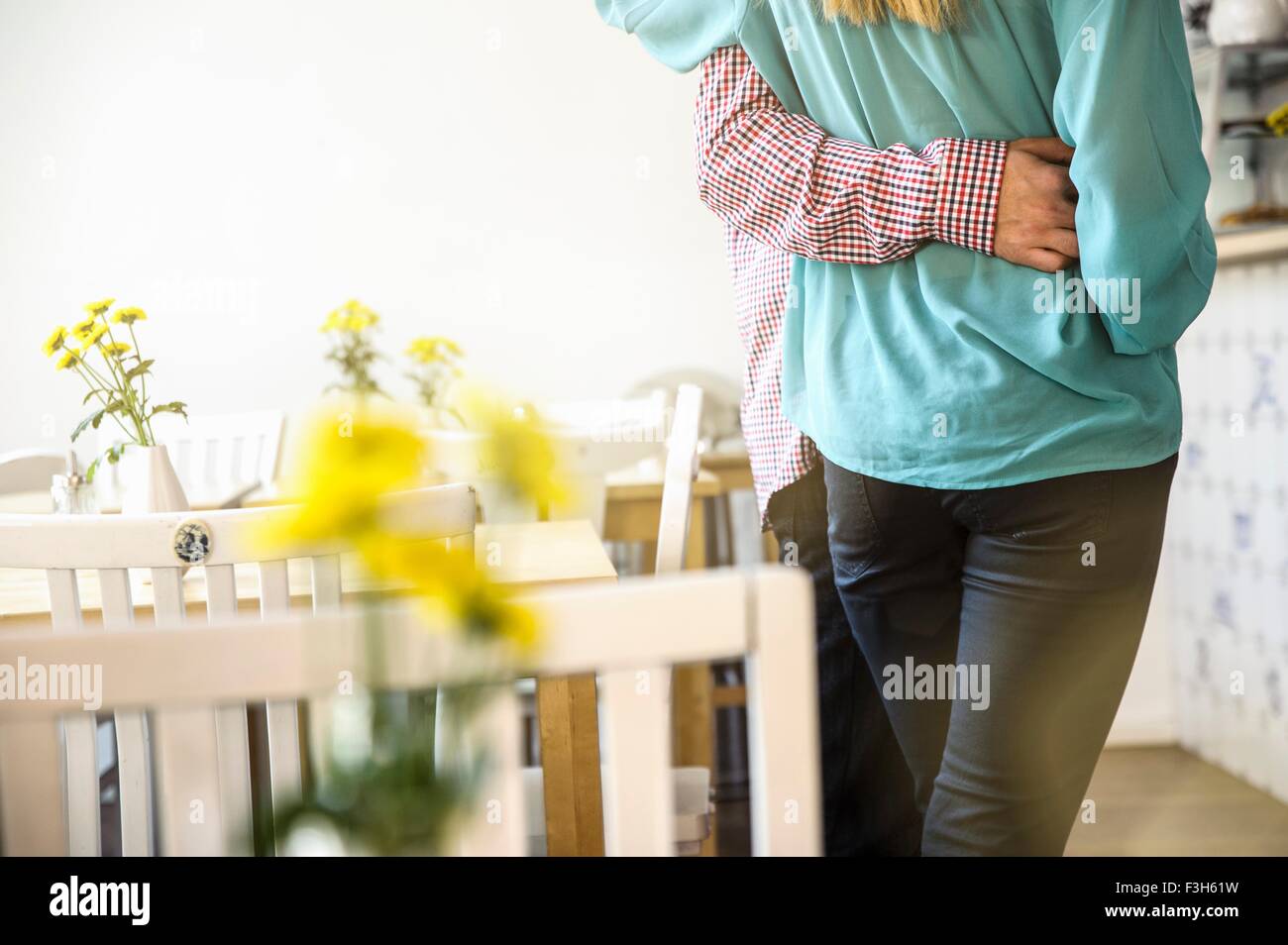 Vue arrière de jeunes couples mid section standing in cafe, le bras autour de la taille Banque D'Images