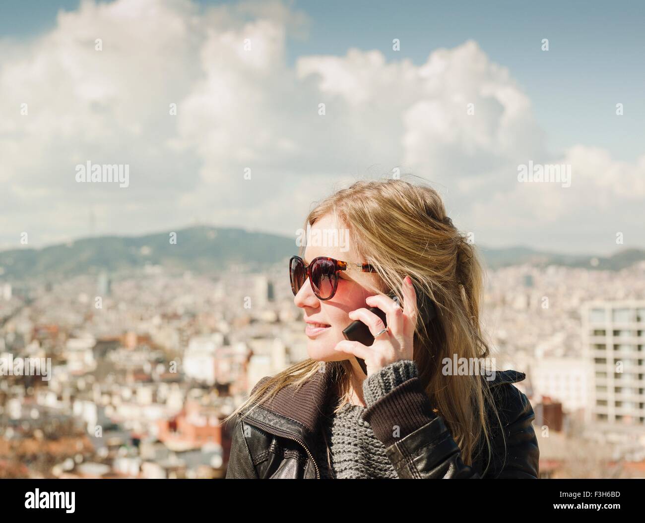 Woman talking on smartphone dans l'avant du paysage urbain à partir de la colline de Montjuic, Barcelone, Espagne Banque D'Images