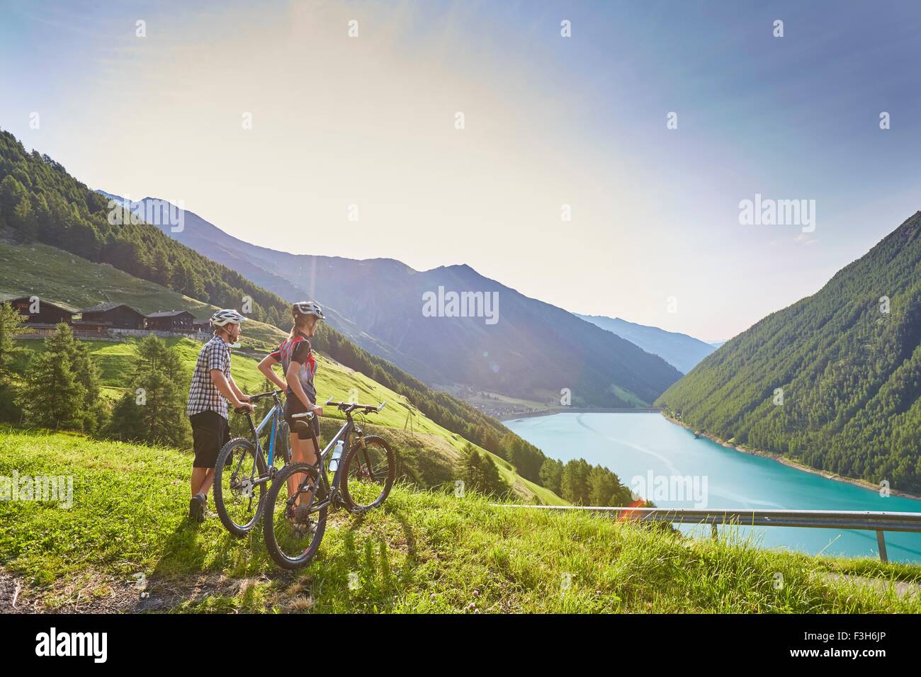 Les jeunes mountain biking couple surplombant Vernagt réservoir et Finailhof ferme, Val Senales, Tyrol du Sud, Italie Banque D'Images