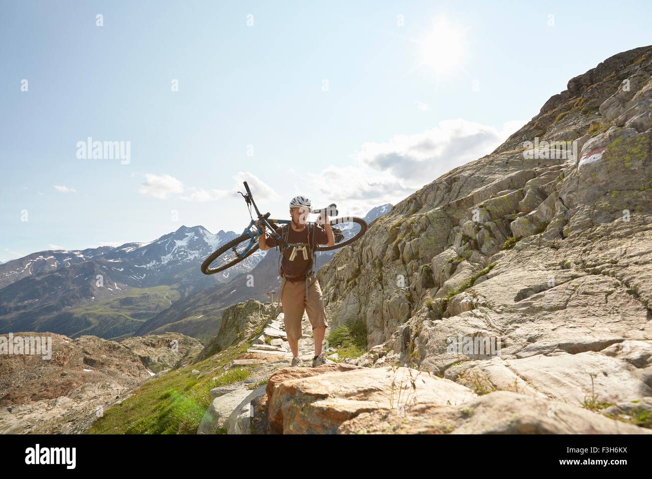 Young man carrying vtt jusqu'au chemin du glacier de Val Senales, Val Senales, Tyrol du Sud, Italie Banque D'Images