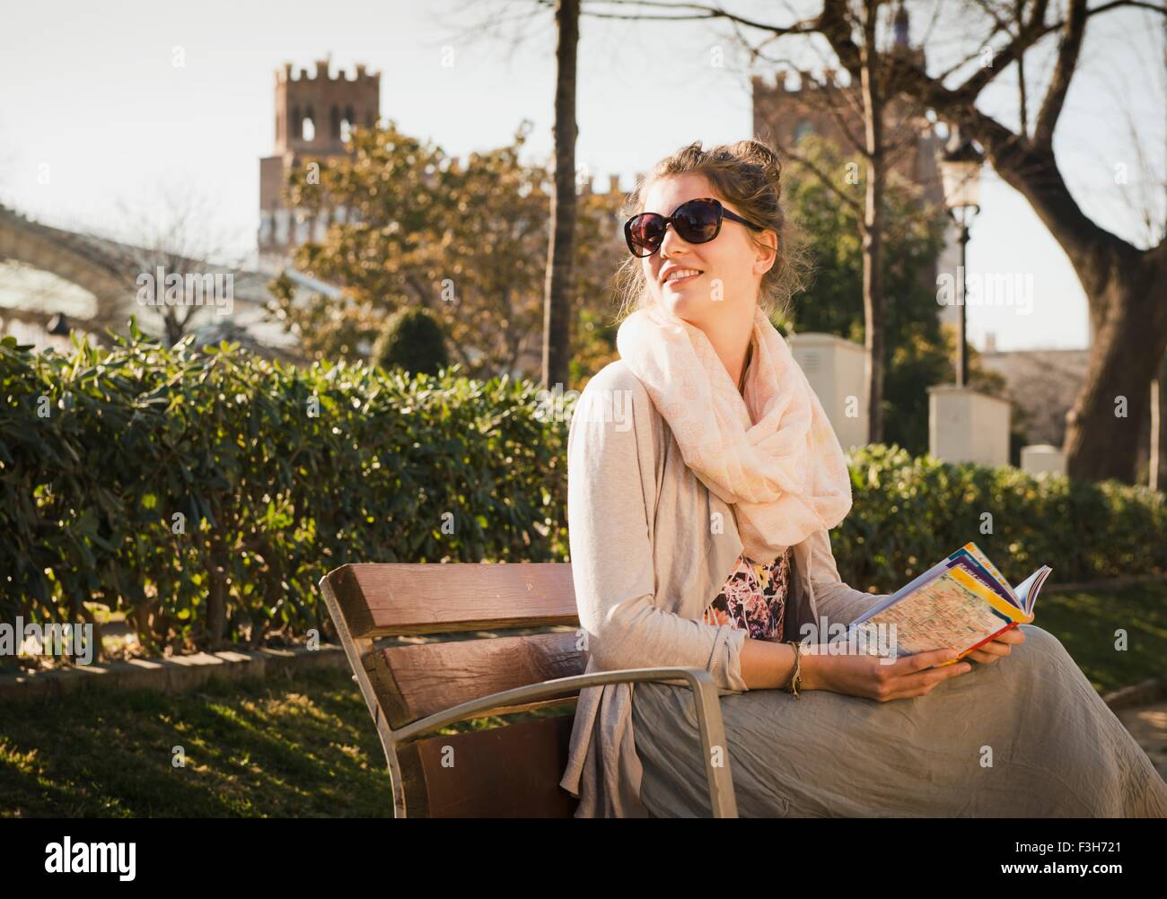 Young woman reading book sur banc, Parc de la Ciutadella, Barcelone, Espagne Banque D'Images