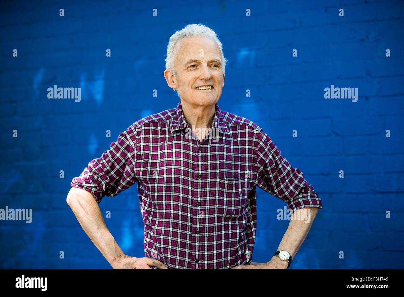 Portrait of happy senior man, mur de brique bleu en arrière-plan Banque D'Images