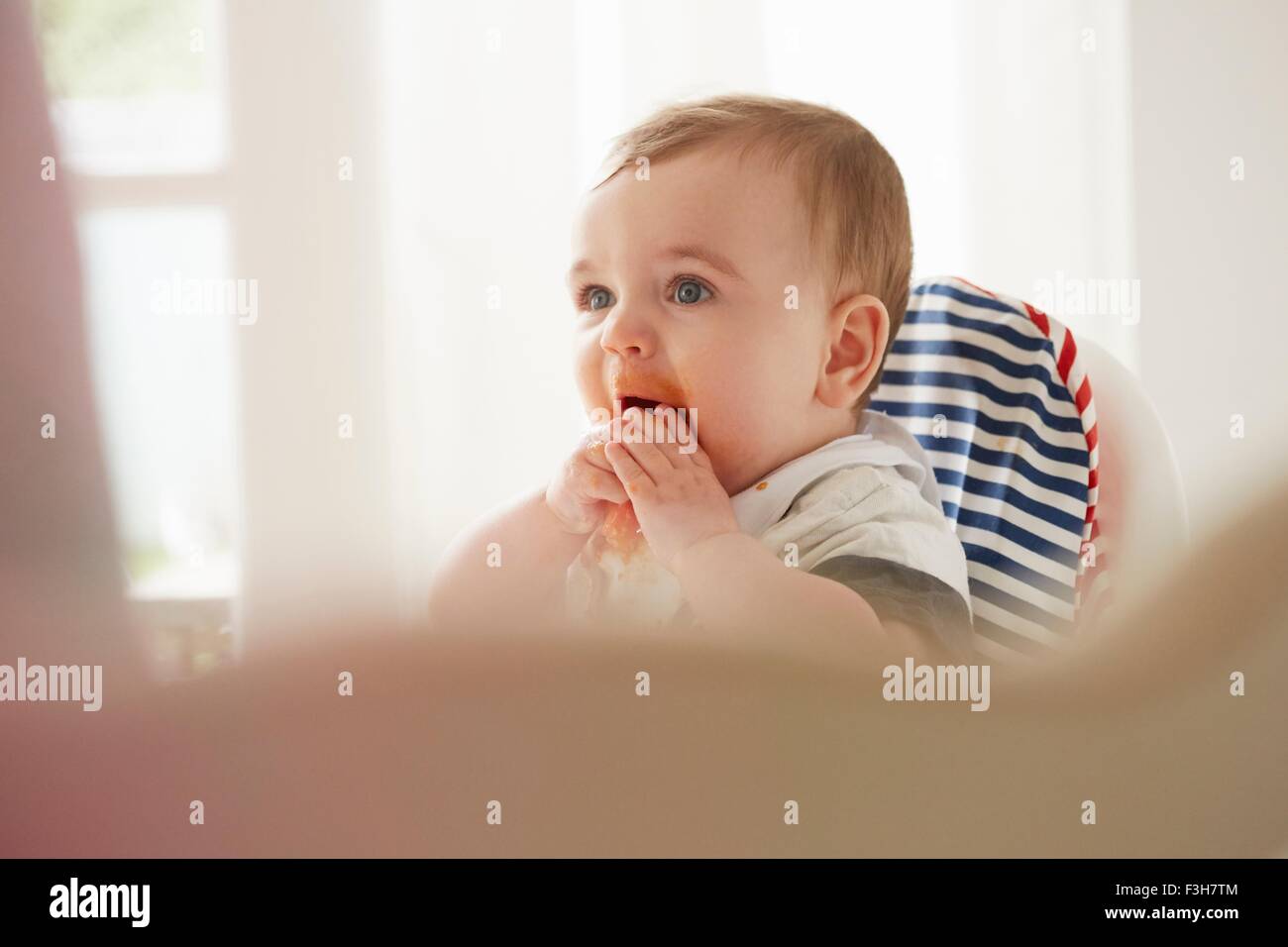 Alimentation Bébé garçon lui-même en chaise de bébé Banque D'Images