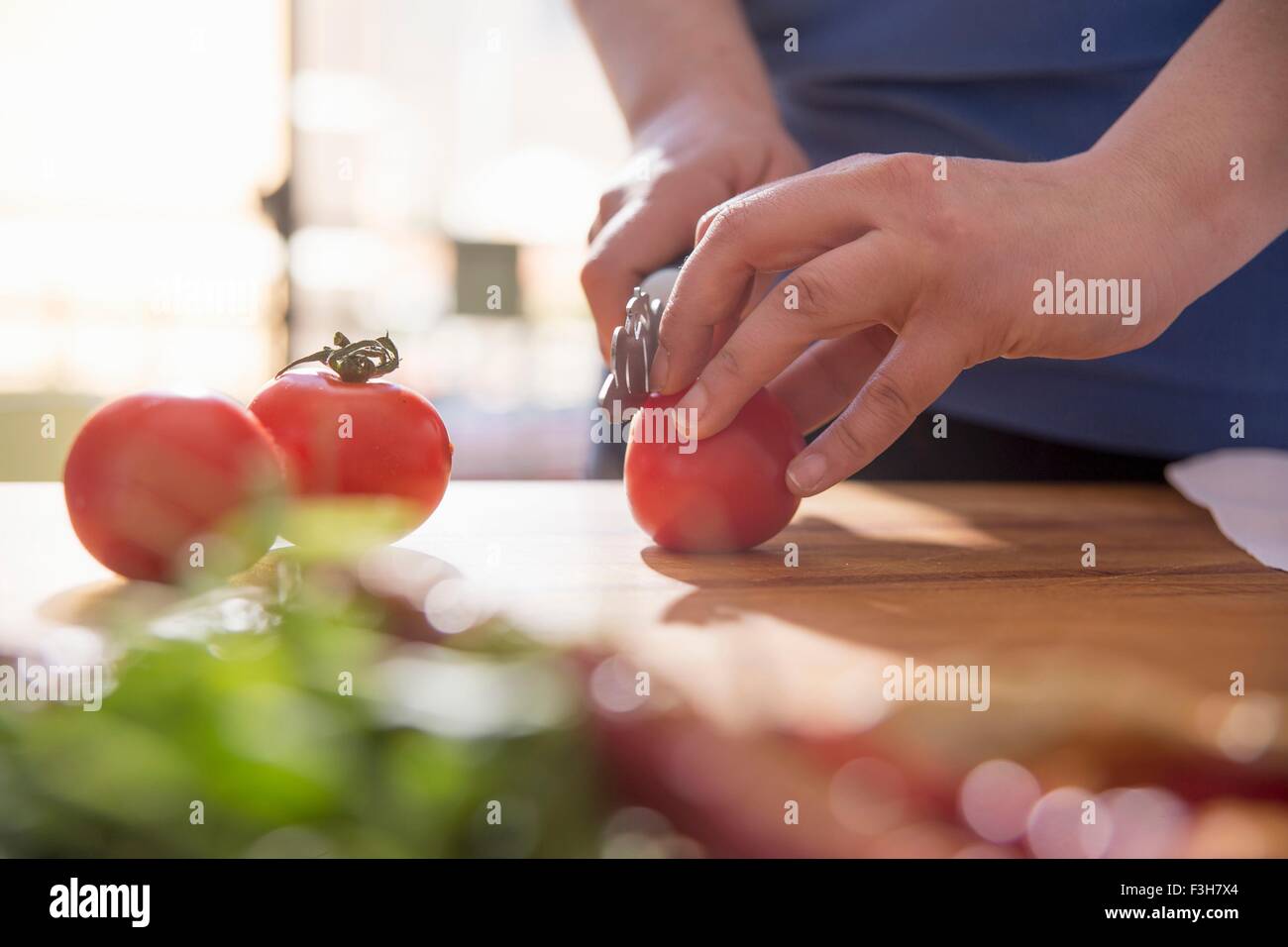 Mains de femme au comptoir de la cuisine de la tomate en tranches Banque D'Images