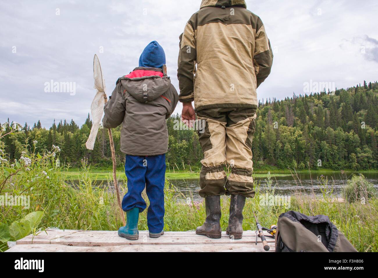Père et fils standing on jetty avec équipement de pêche, vue arrière Banque D'Images