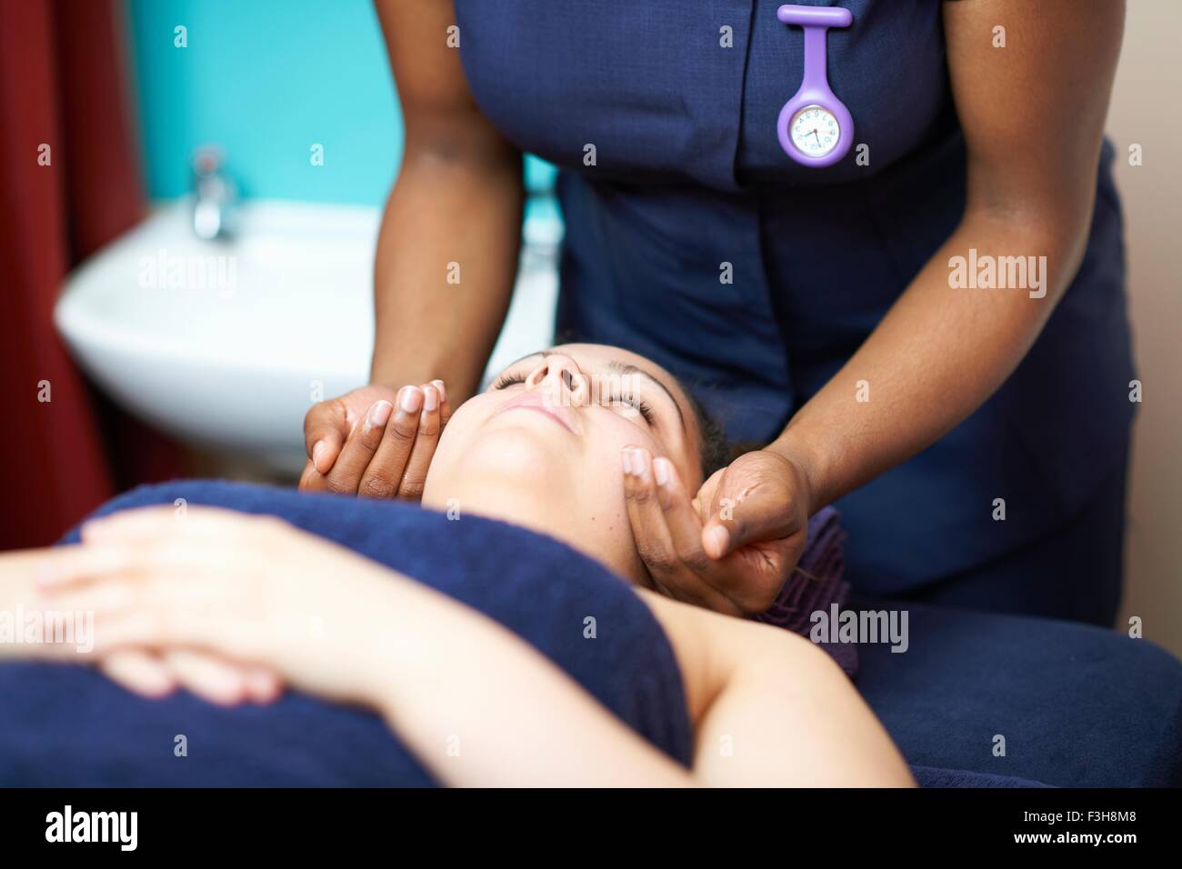 Tête et épaules de jeune femme couchée ayant massage du visage, les yeux fermés Banque D'Images