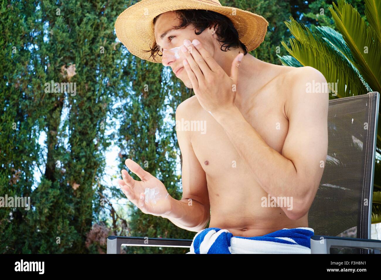 Jeune homme portant chapeau contre l'application de la crème solaire à face Banque D'Images