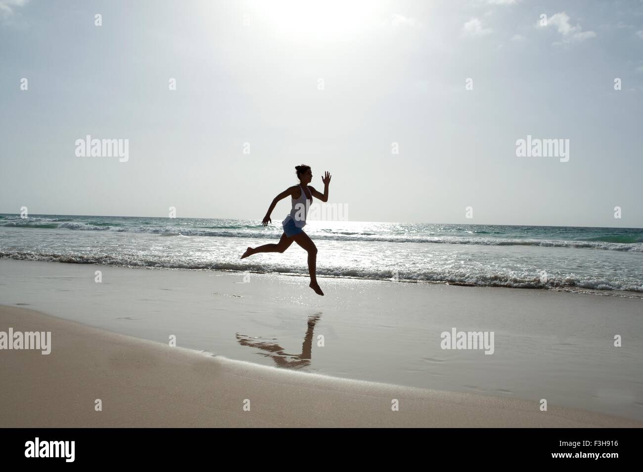 La silhouette du Mid adult woman running barefoot on beach, Cap Vert, Afrique Banque D'Images