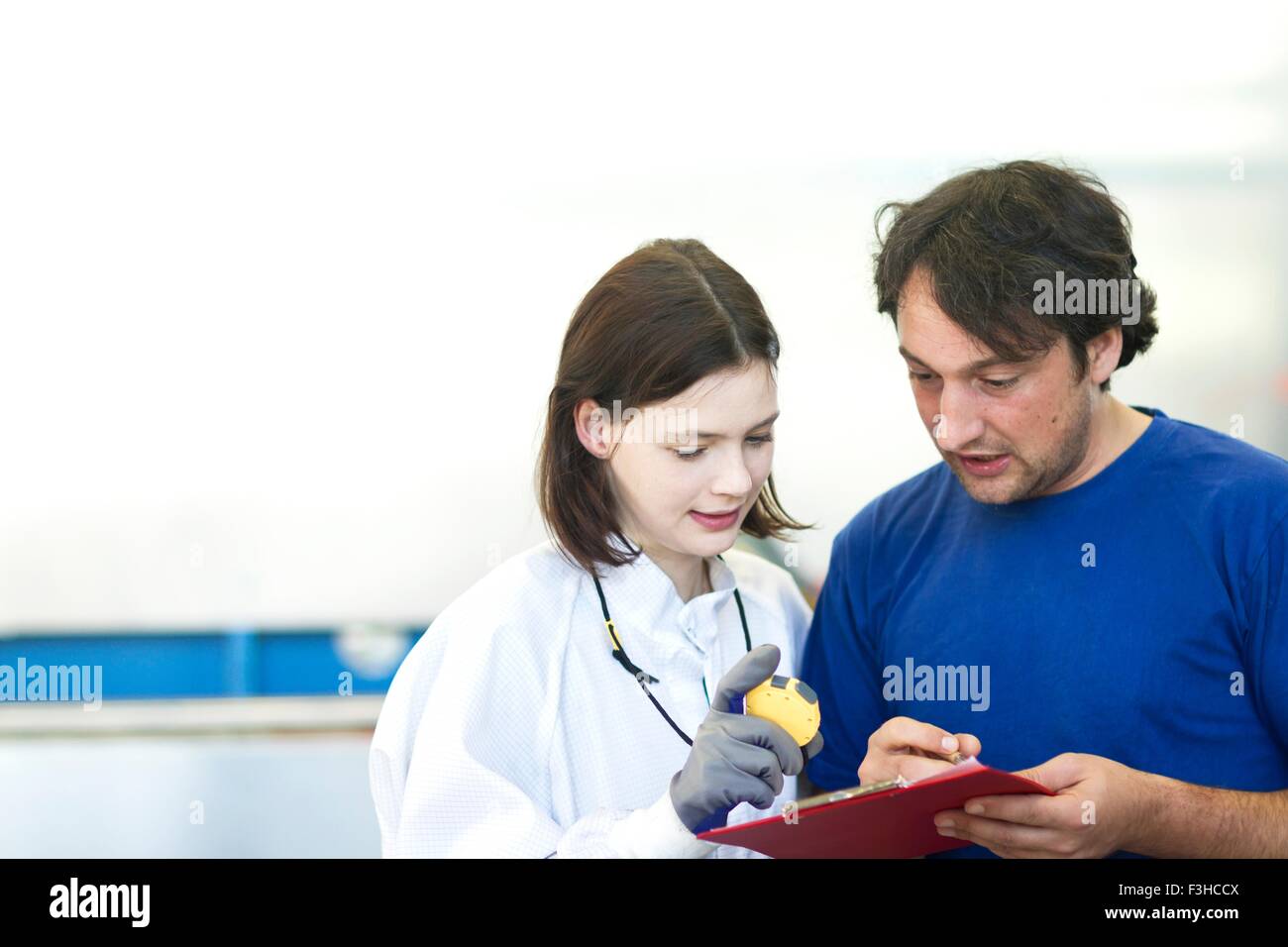 Collègues masculins et féminins à l'inspection de la boîte de pétri, writing on clipboard Banque D'Images