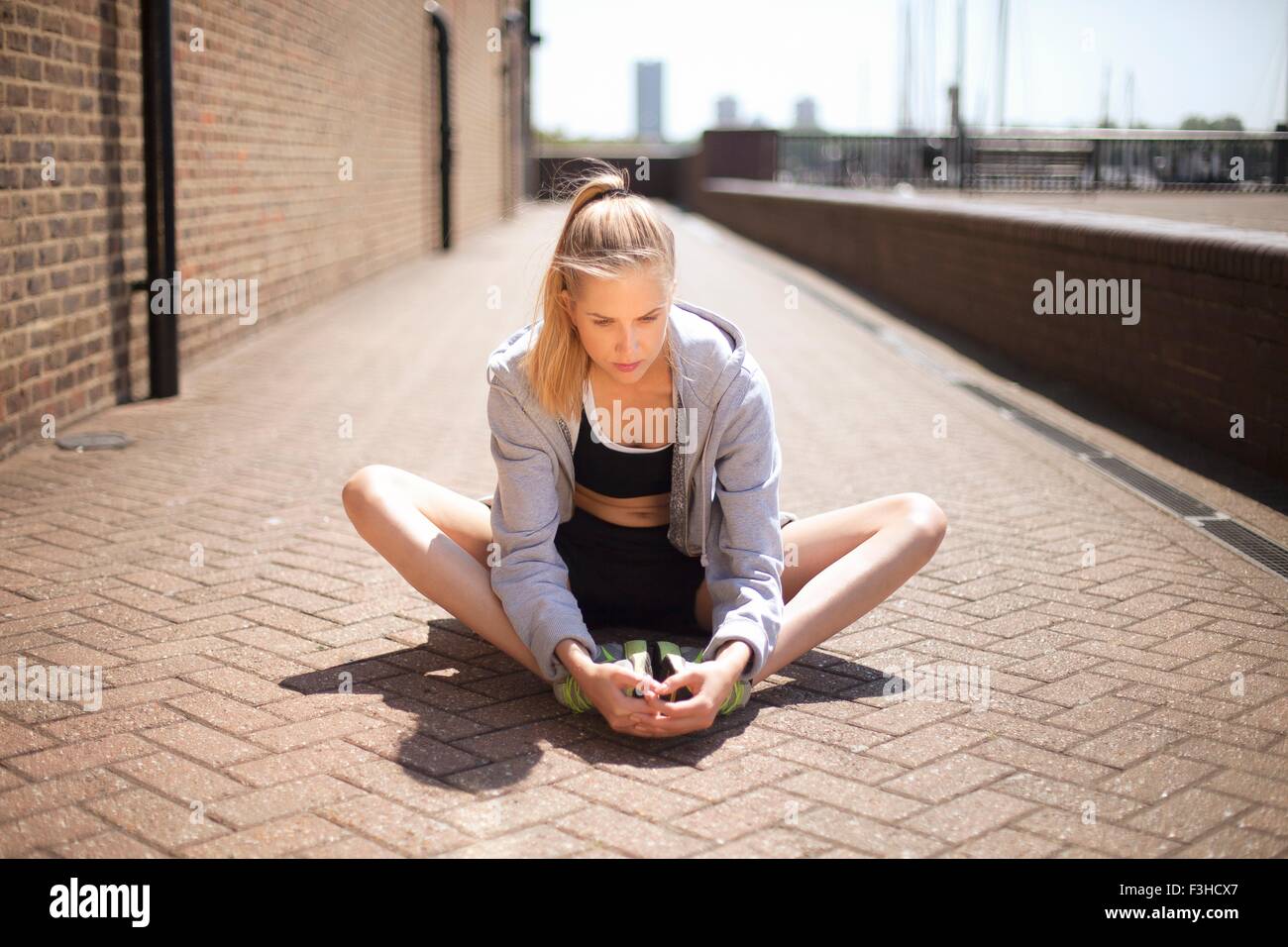 Runner stretching sur passerelle, Wapping, Londres Banque D'Images