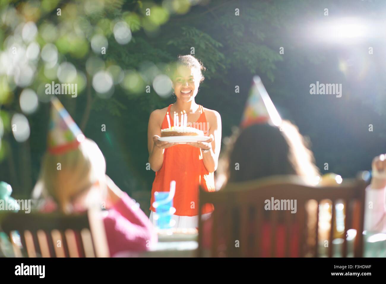 Mère portant le gâteau d'anniversaire à la table au jardin d'anniversaire Banque D'Images