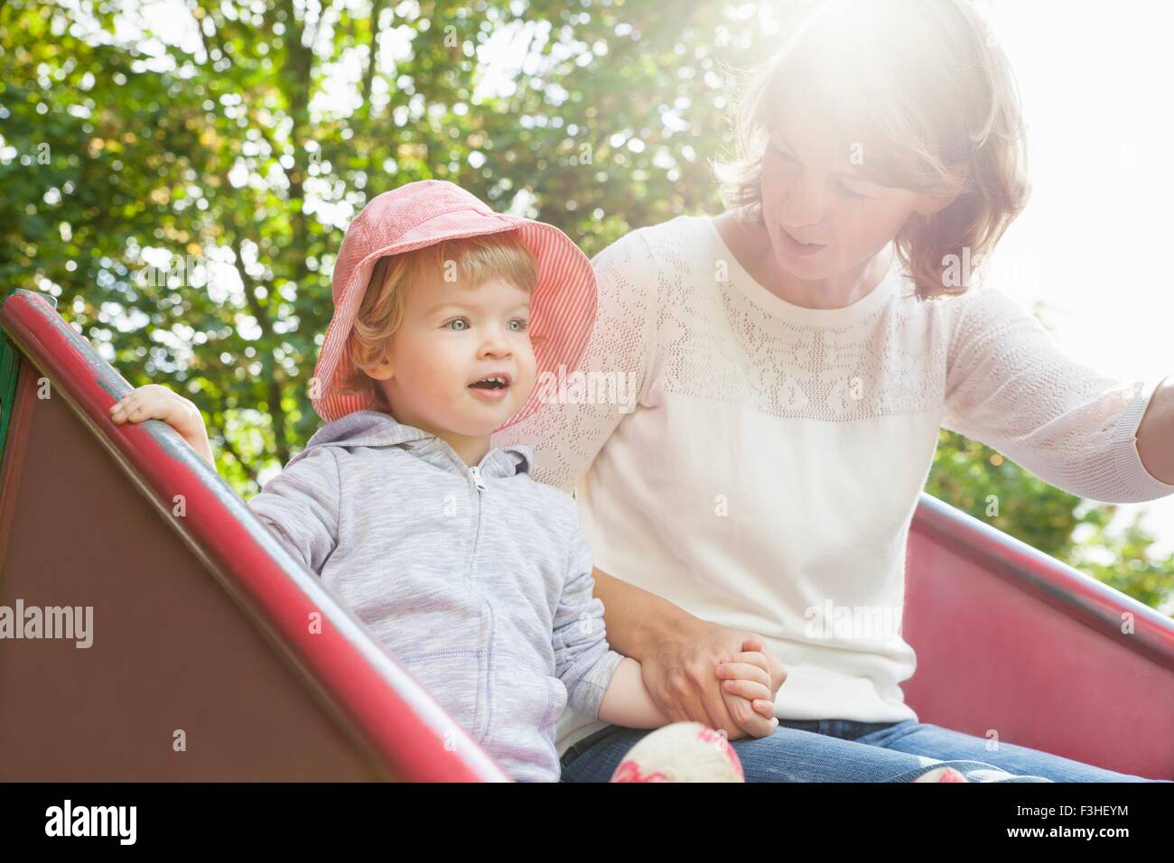 Mère et femme enfant jouant sur park slide Banque D'Images