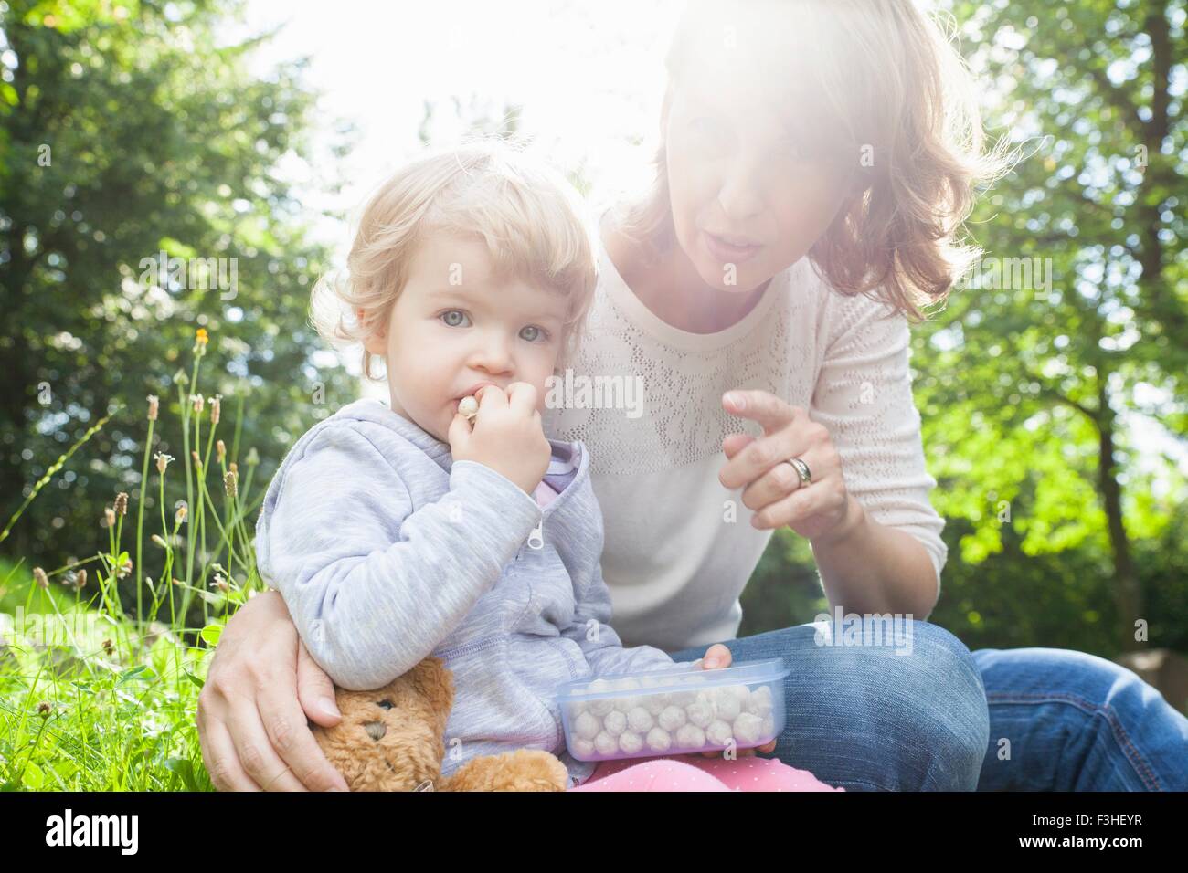 Mère et femme enfant manger des douceurs dans park Banque D'Images