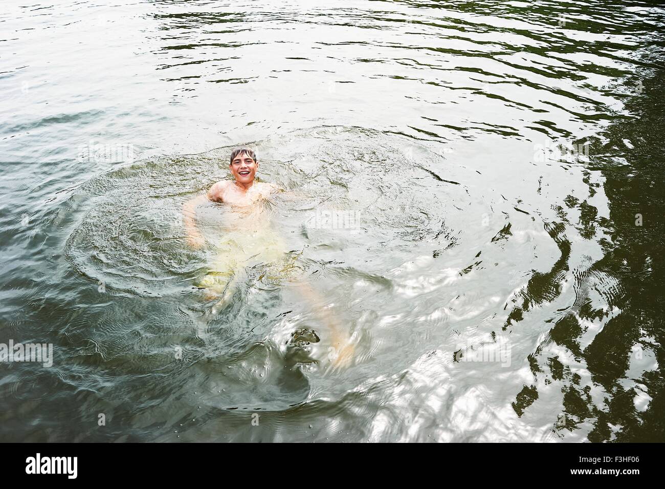 Teenage boy swimming in rural lake Banque D'Images