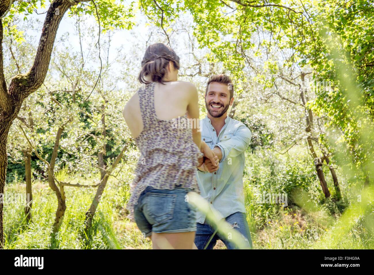 Young couple holding hands in forest fricoter smiling Banque D'Images