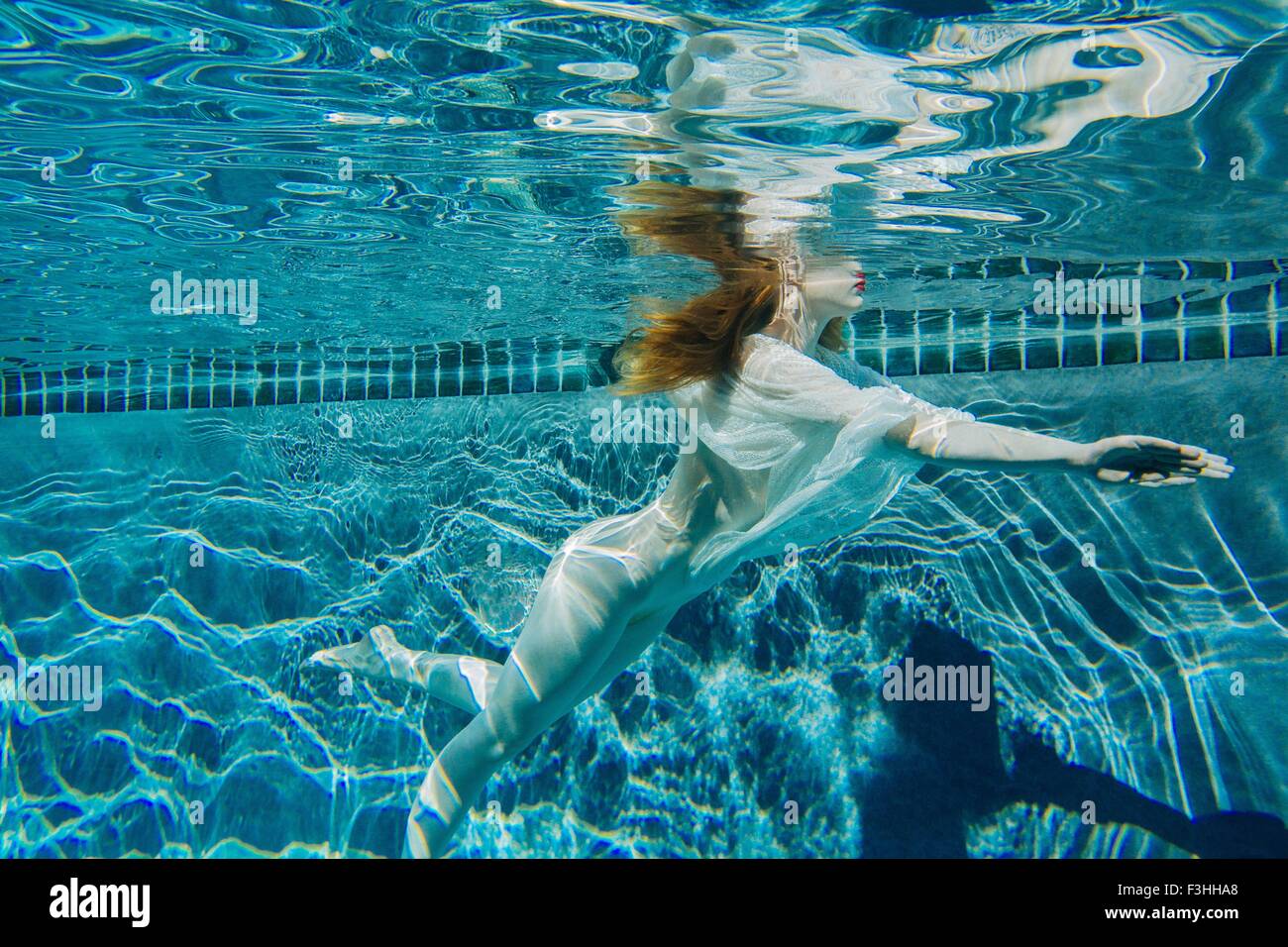Jeune femme nager sous l'eau, portant chemise blanche fine Banque D'Images