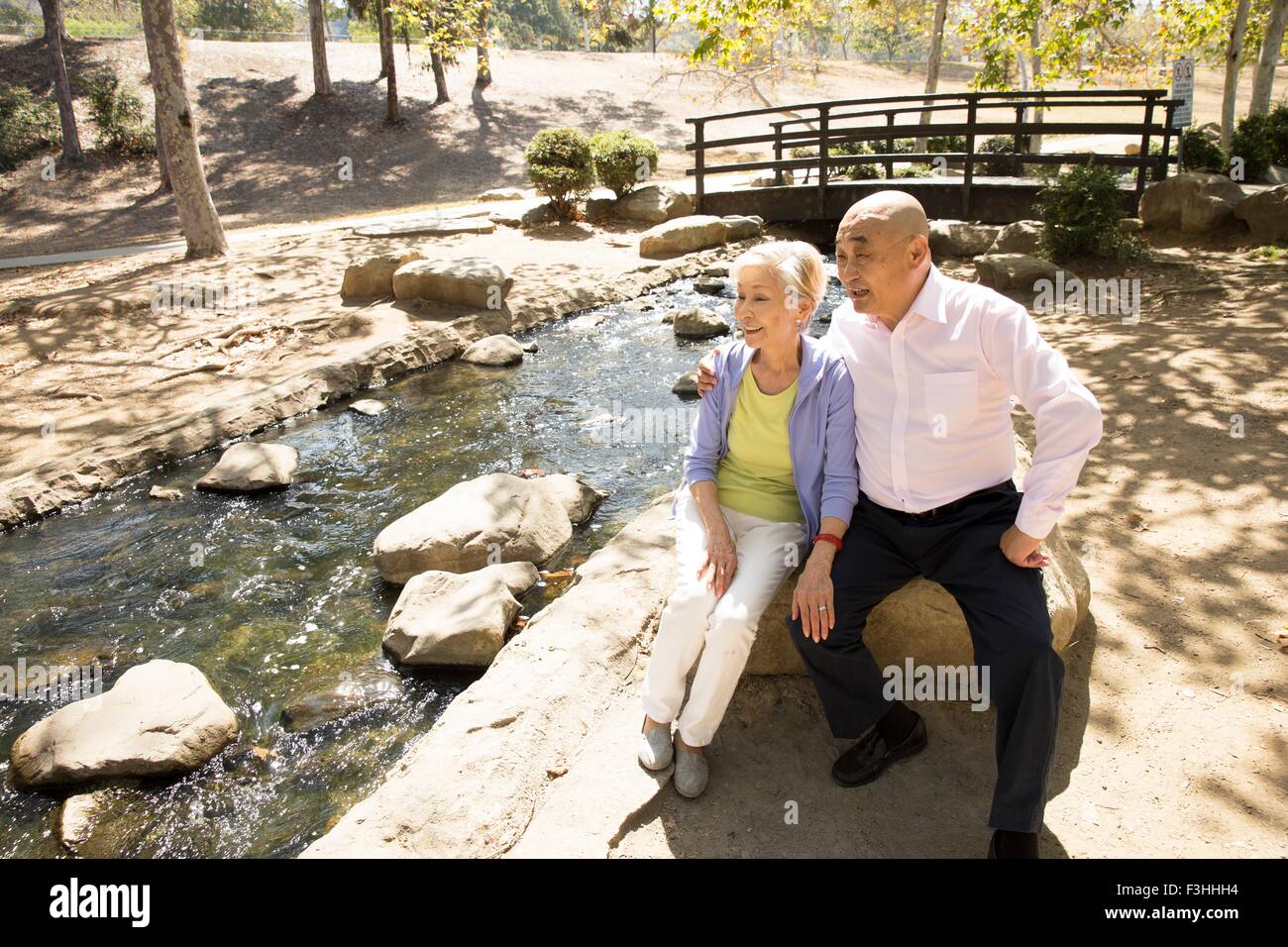 Senior couple sitting on rock à côté de stream Banque D'Images