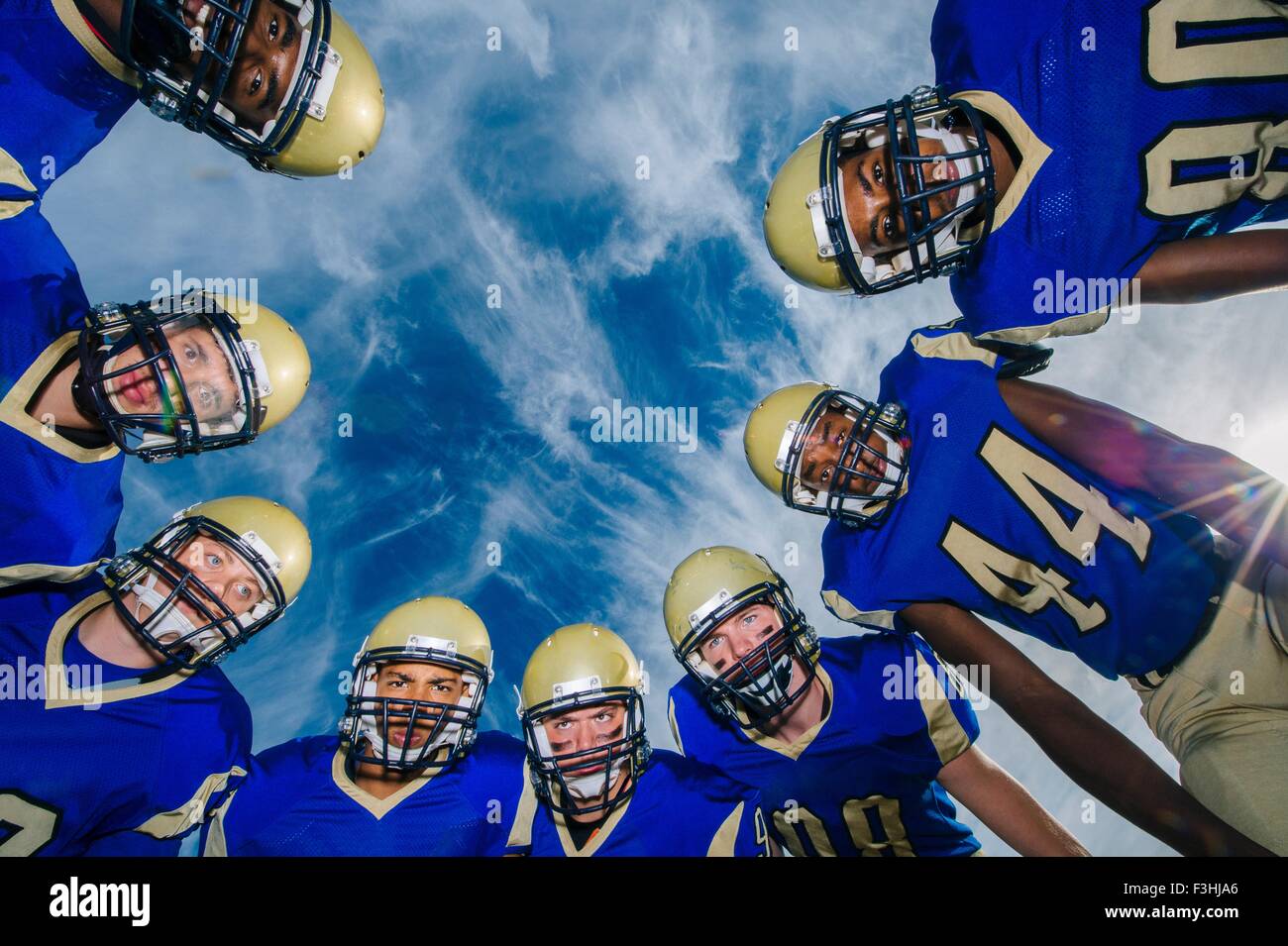 Low angle portrait d'adolescents et adultes de l'équipe de football américain contre le ciel bleu Banque D'Images