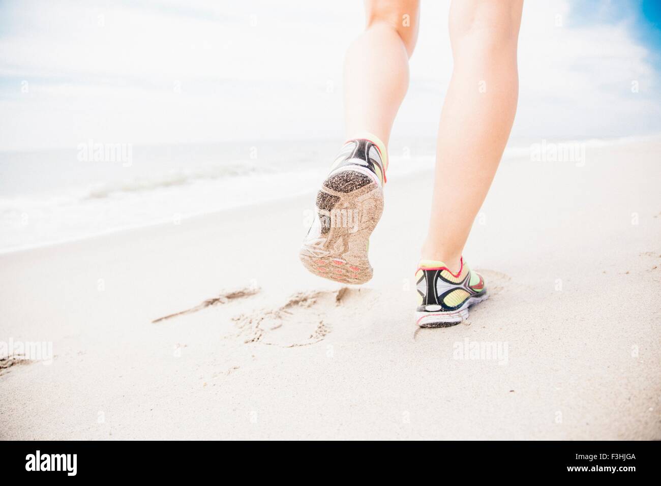 Mid adult woman walking on beach, vue arrière, low section Banque D'Images