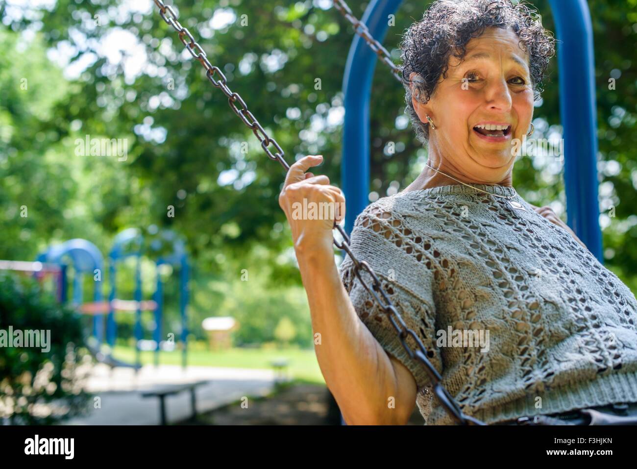 Portrait of senior woman en jouant sur swing park Banque D'Images